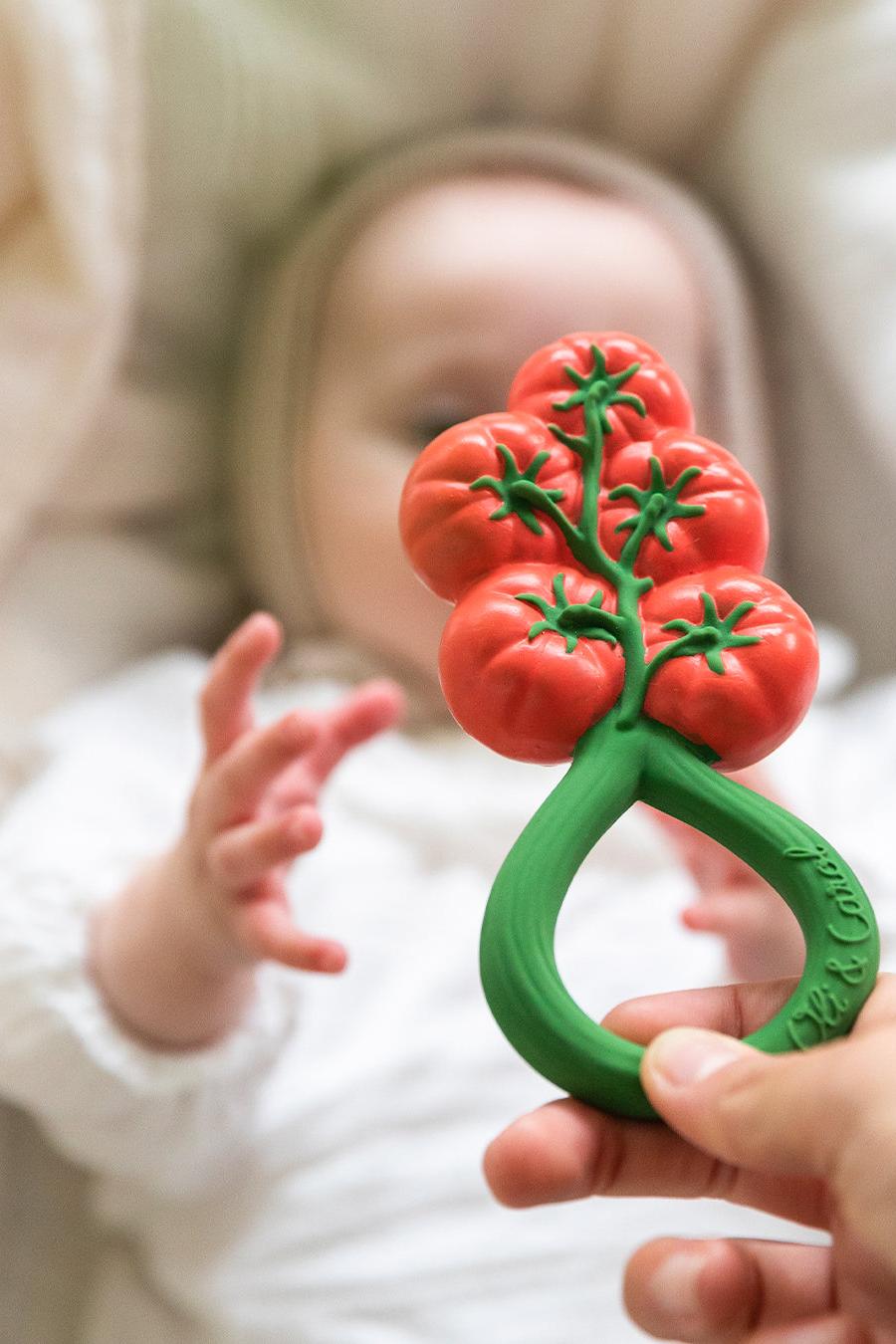 Tomato-shaped baby rattle and teether held by adult