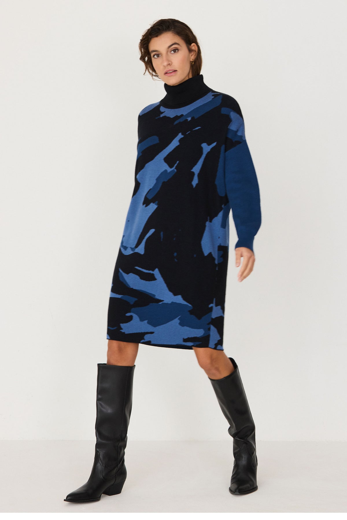 Woman wearing a SKFK black and blue cotton knit dress with black knee-high boots