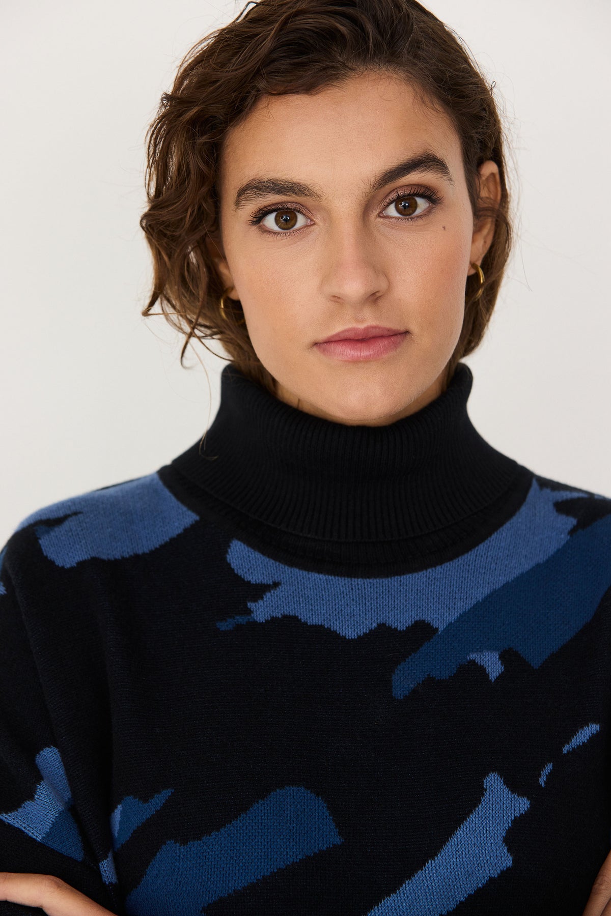 A woman wearing a SKFK black and blue patterned cotton knit turtleneck dress.