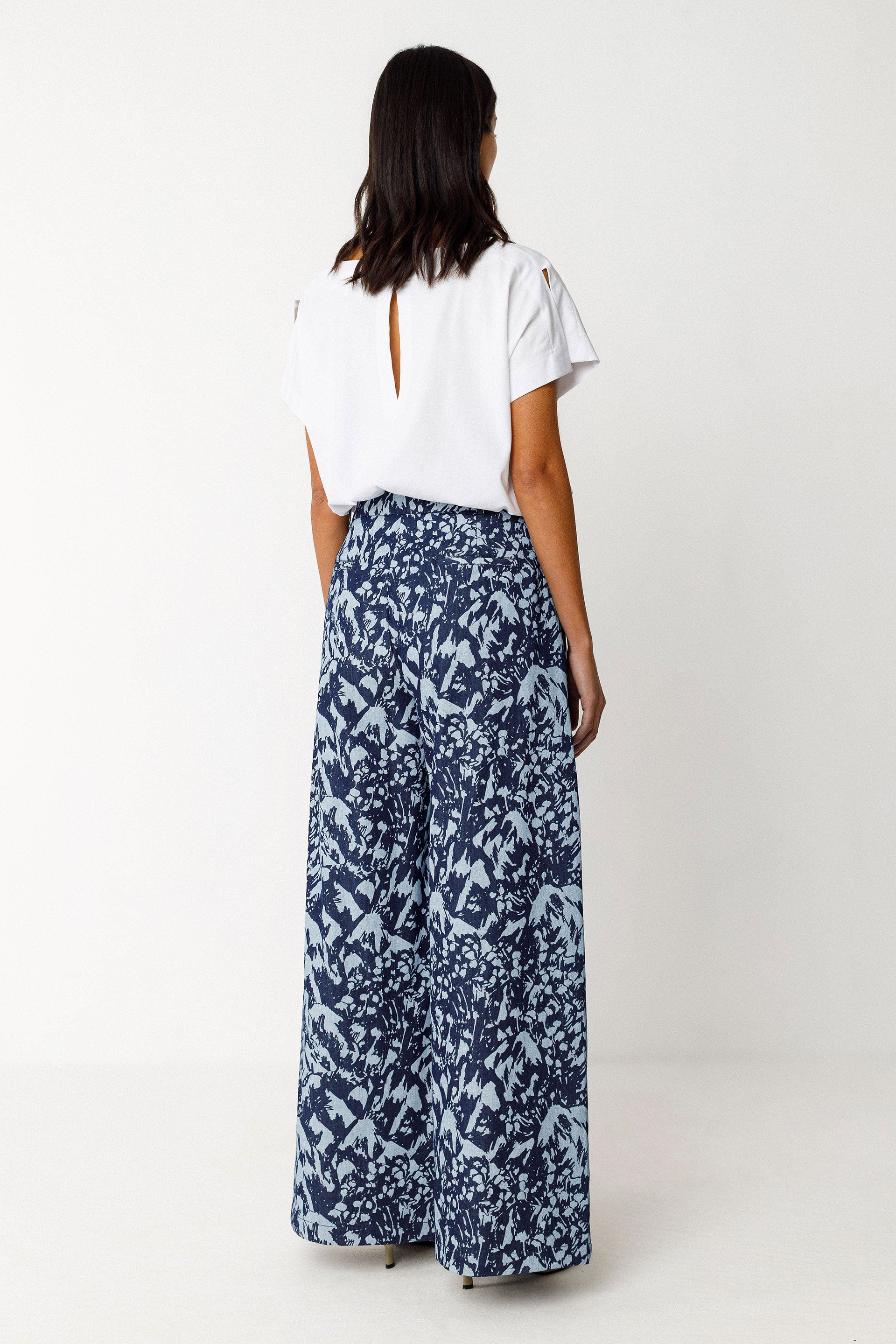 Person wearing a white t-shirt and blue patterned organic cotton pants on a white background