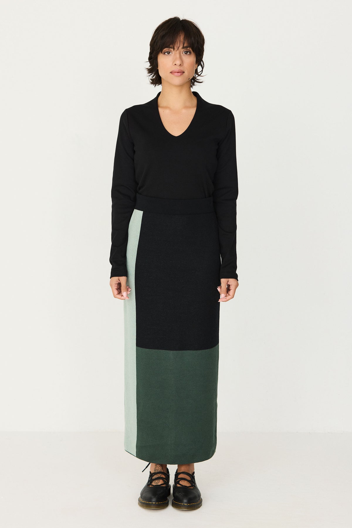 A woman from behind wearing a colour-blocked ankle-length green and black cotton knit skirt by SKFK.