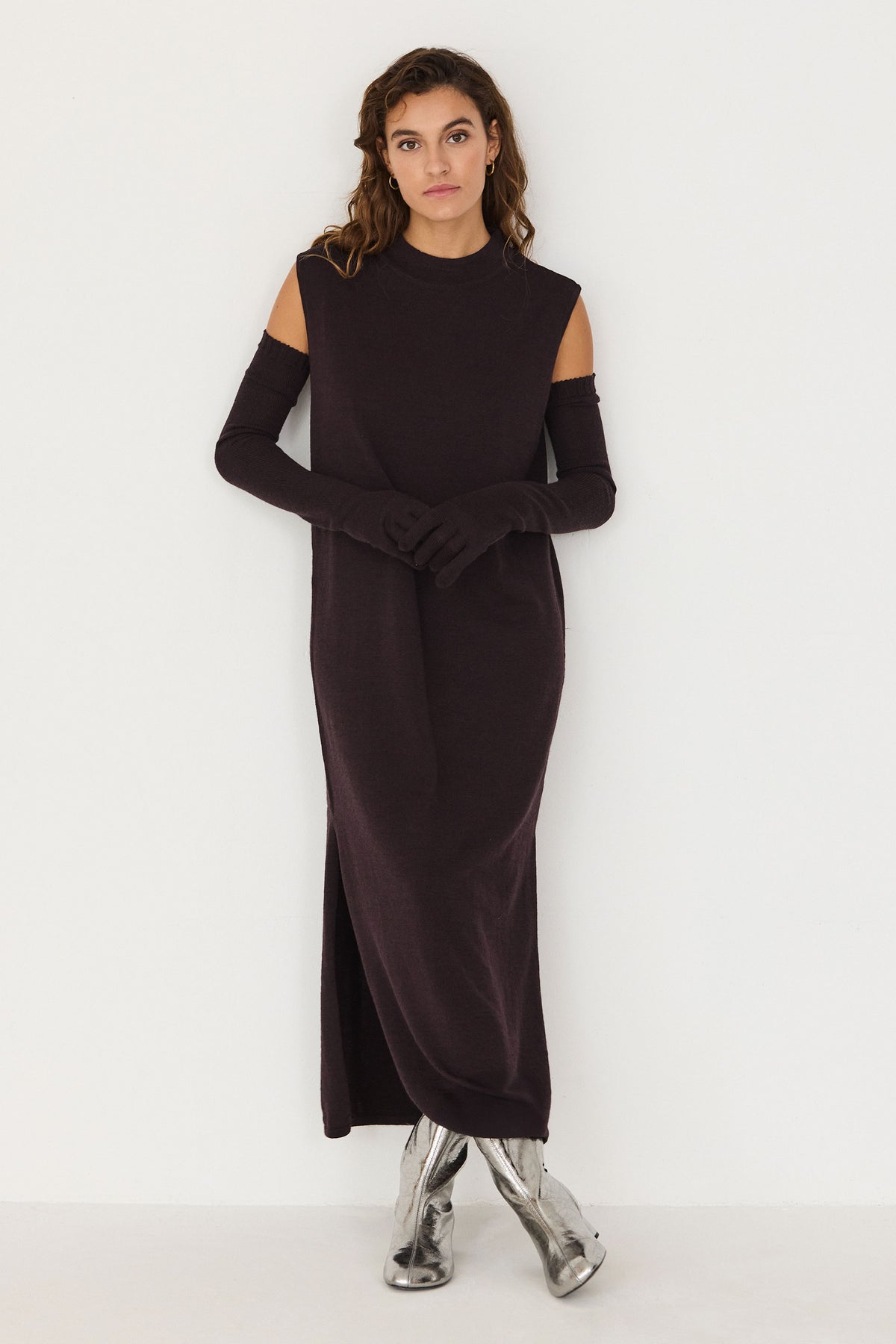 Woman wearing a brown merino wool sleeveless evening dress with matching arm warmers against a white background.