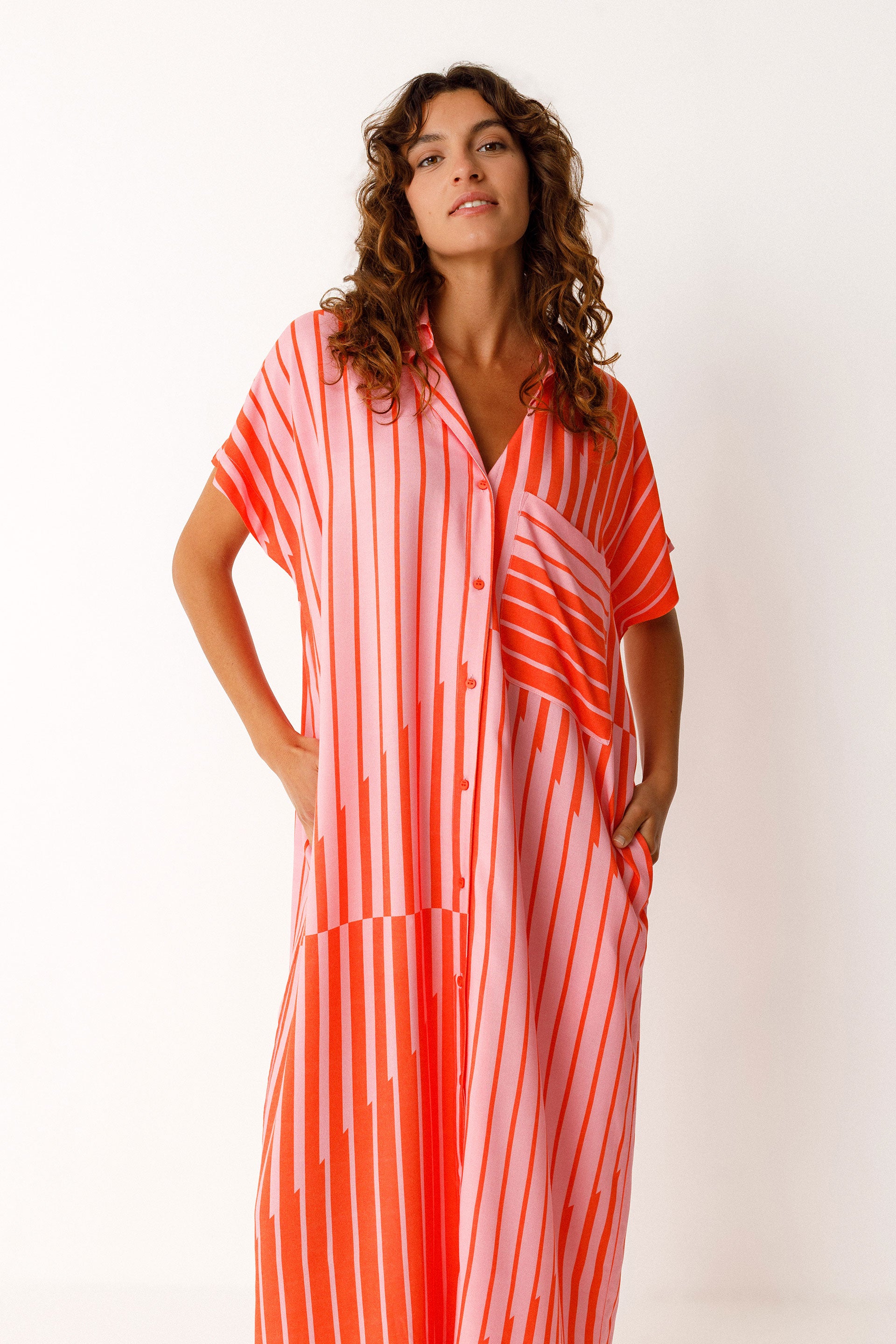 Woman wearing a red and pink striped SKFK dress against a white background