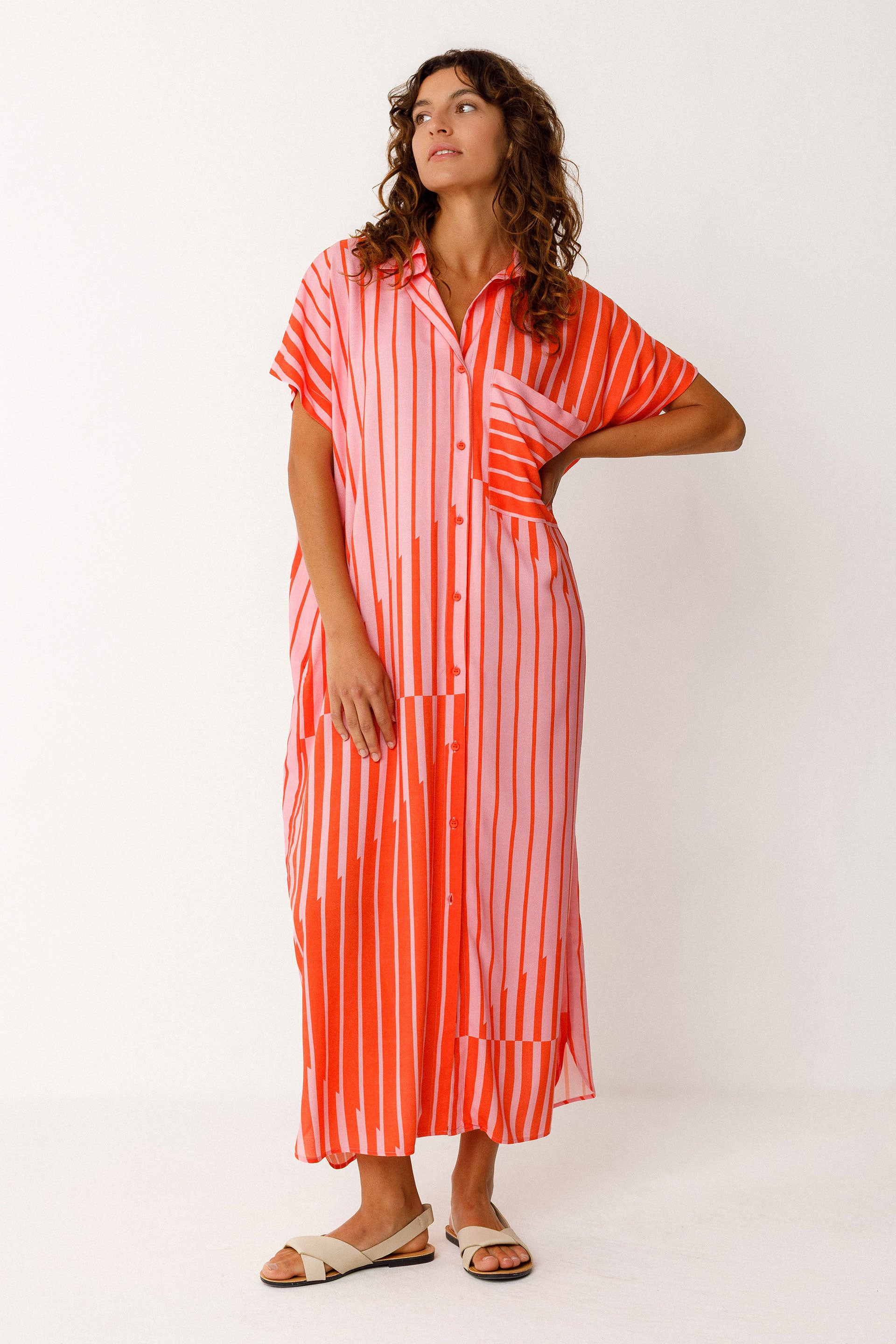 Woman wearing a red and pink striped maxi dress on a white background