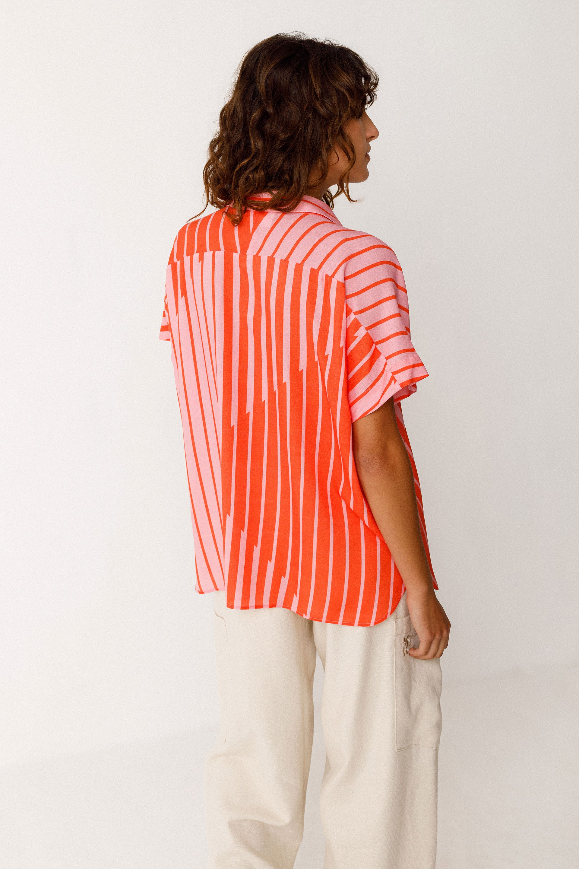 Model wearing a red and pink striped SKFK shirt against a white background