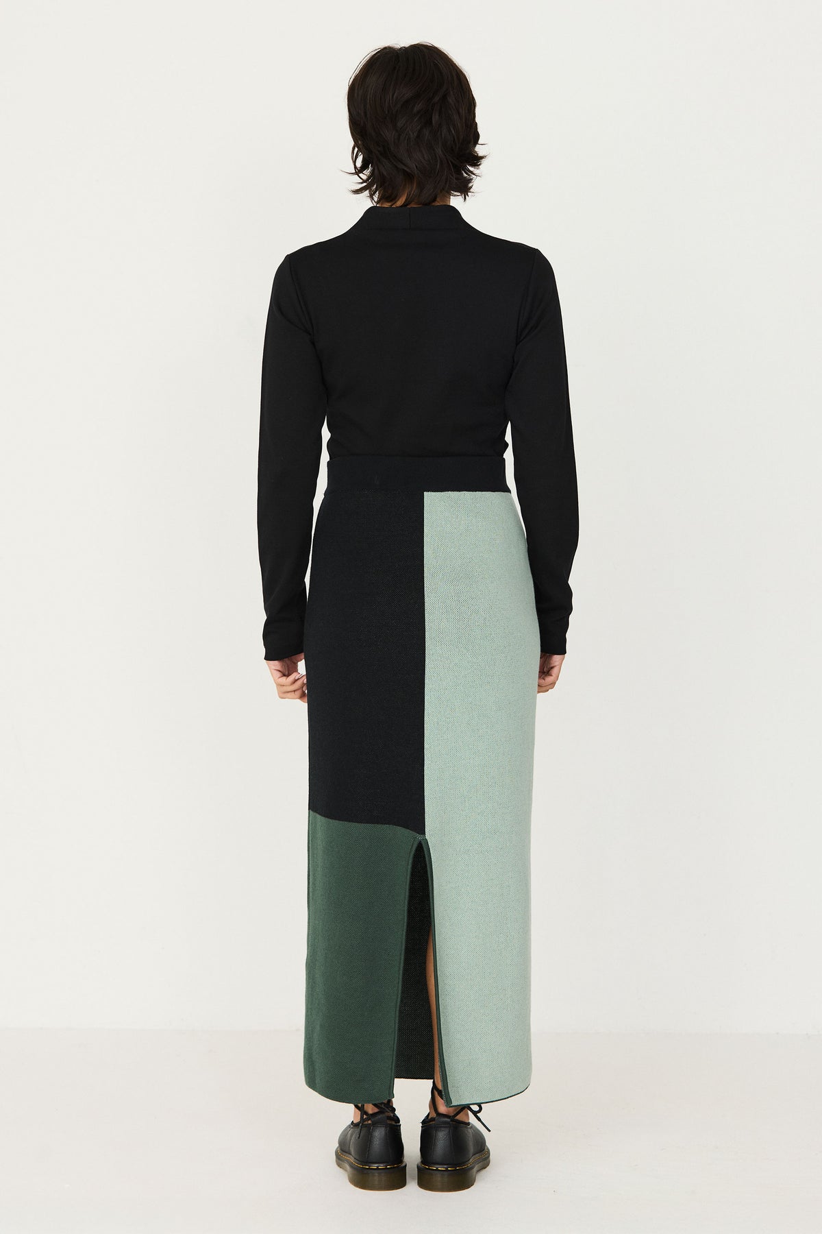 Woman wearing a green and black colourblock cotton knit long skirt with a black long-sleeve top.