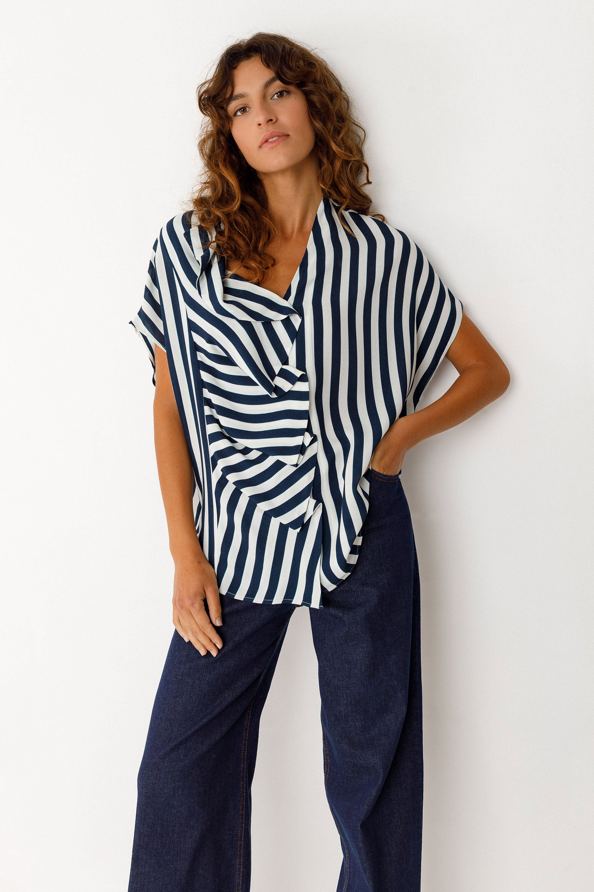 Woman wearing a navy and white striped top with navy pants on a white background