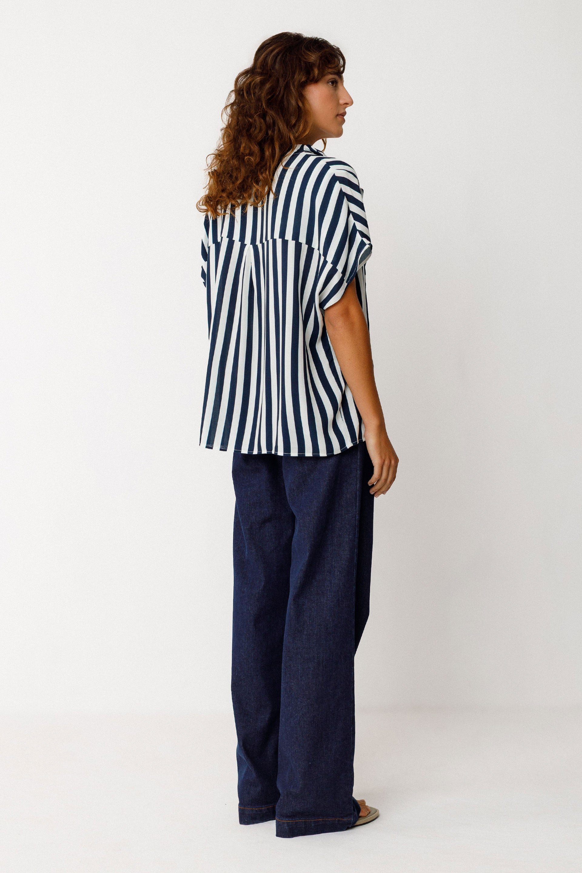 Person wearing a navy and white striped shirt and navy pants on a white background