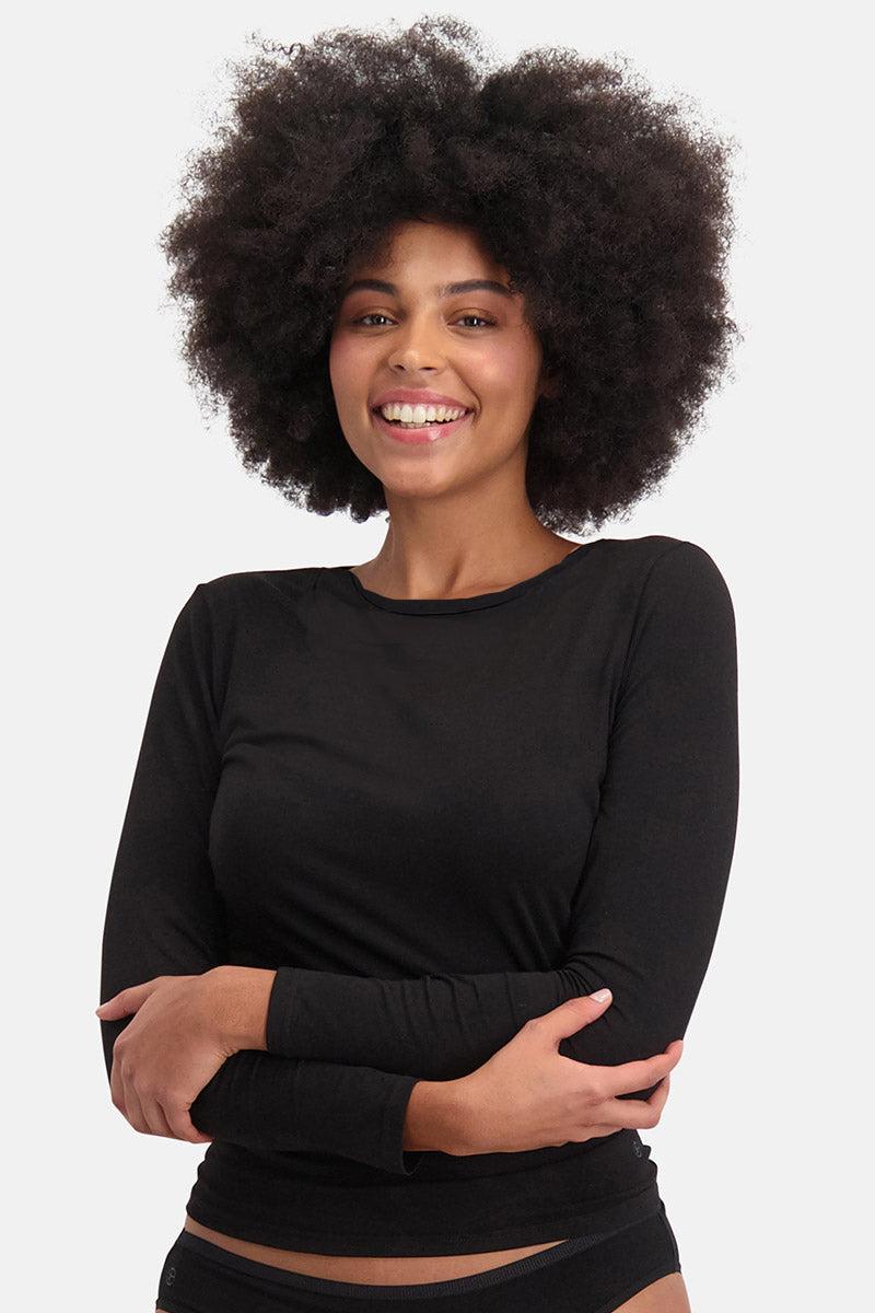 Smiling woman with a large afro wearing a black bamboo long-sleeve shirt against a white background