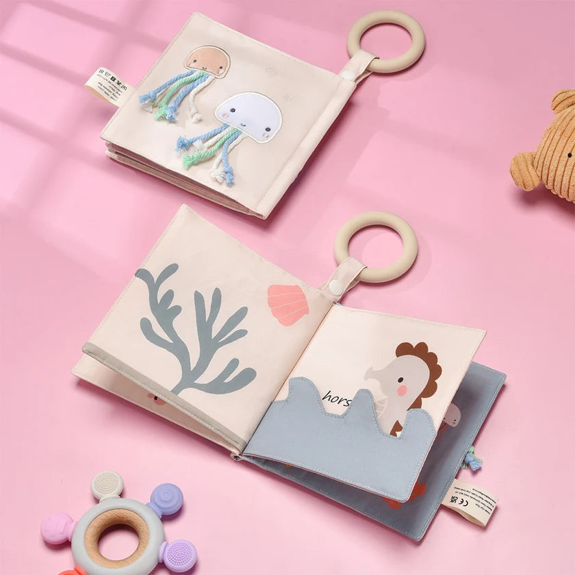 Two soft books with plush toys on a pink background