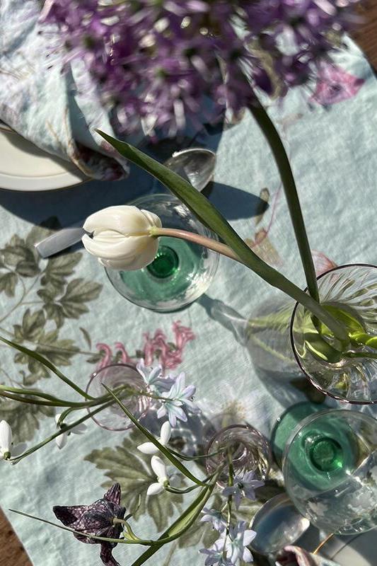 Clear glass bottles with green liquid on a floral tablecloth