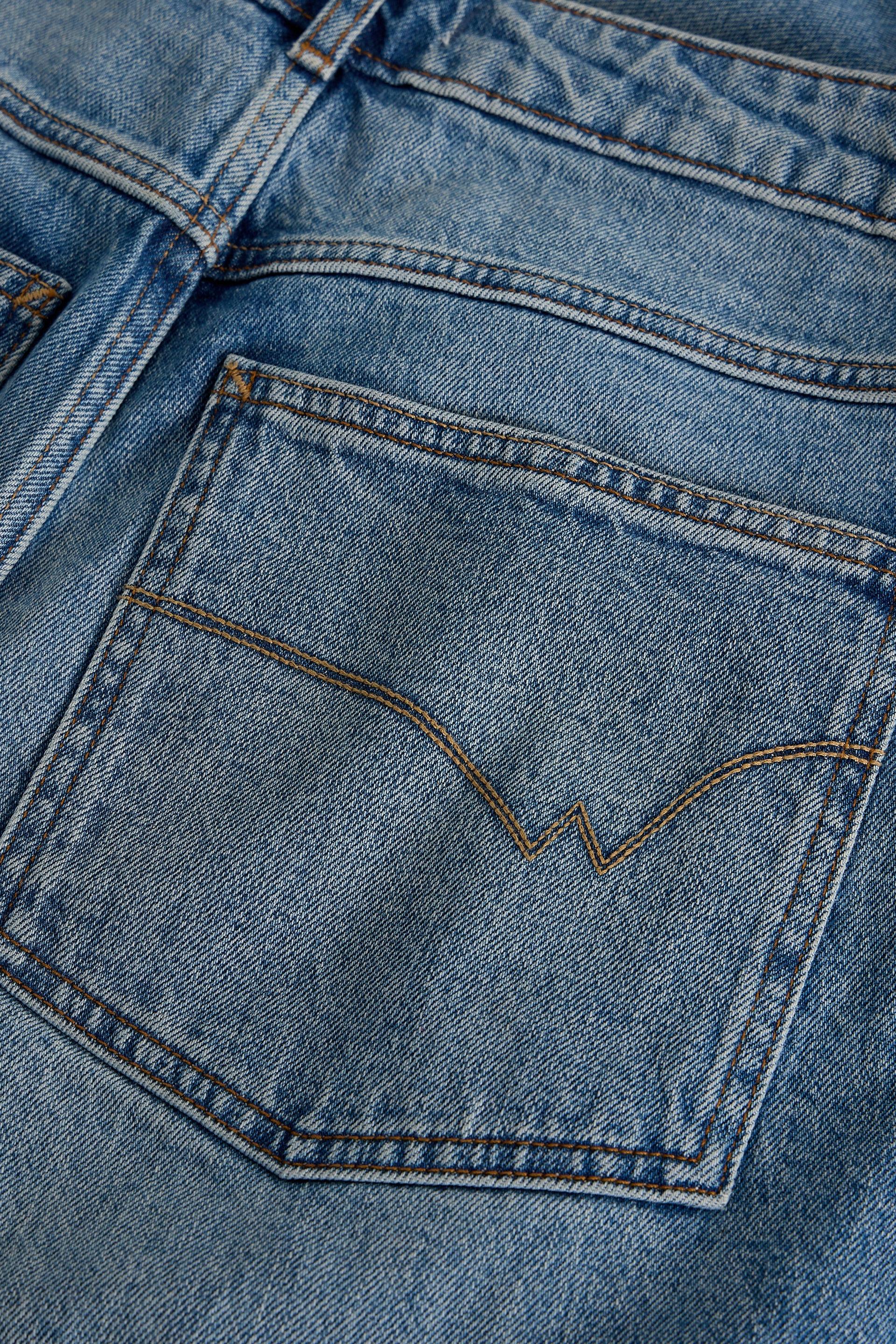 Close-up of a blue denim pocket with brand logo