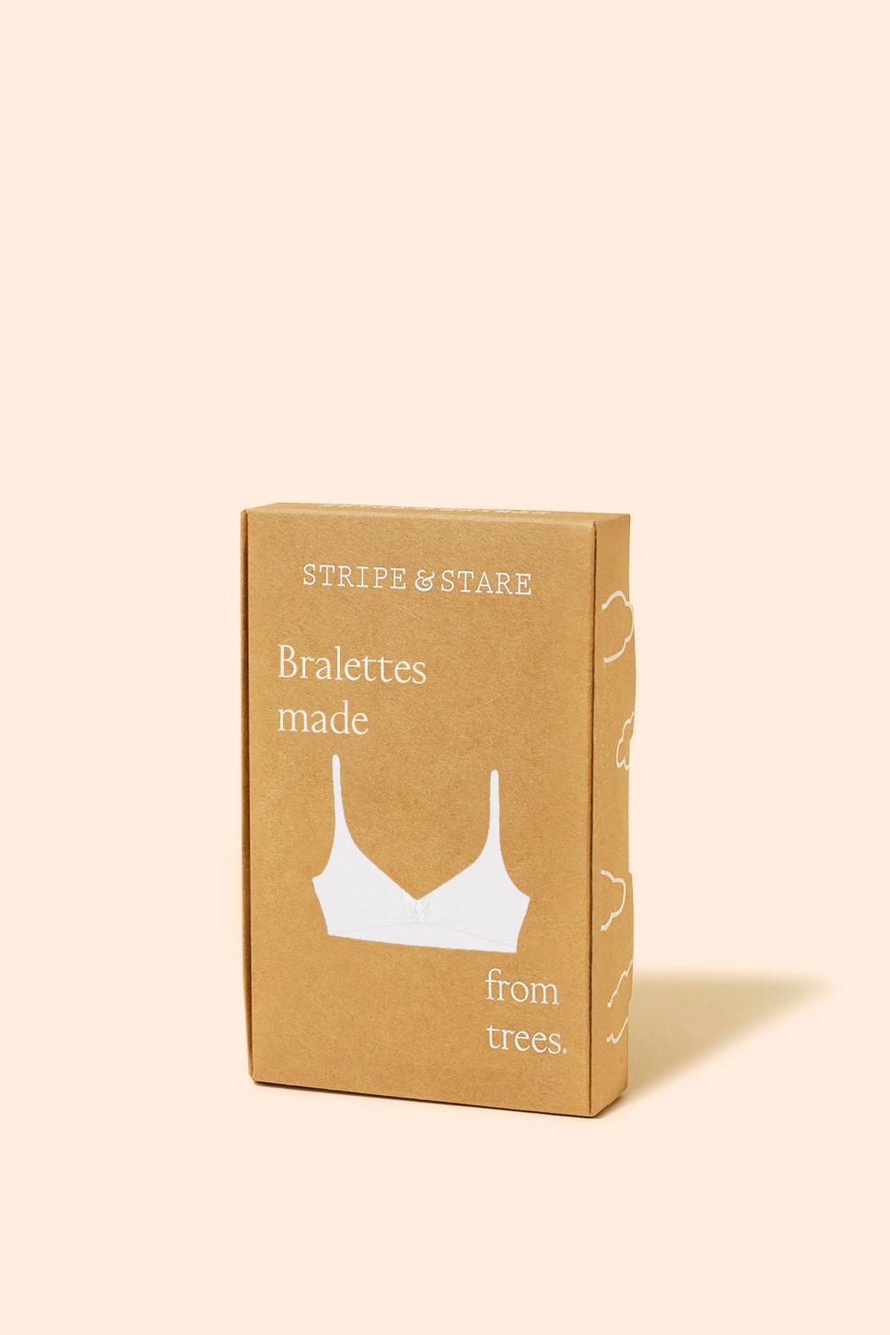 A kraft paper product box for Stripe & Stare Bralettes made from trees, featuring a white bra silhouette graphic, set against a solid pale peach background.