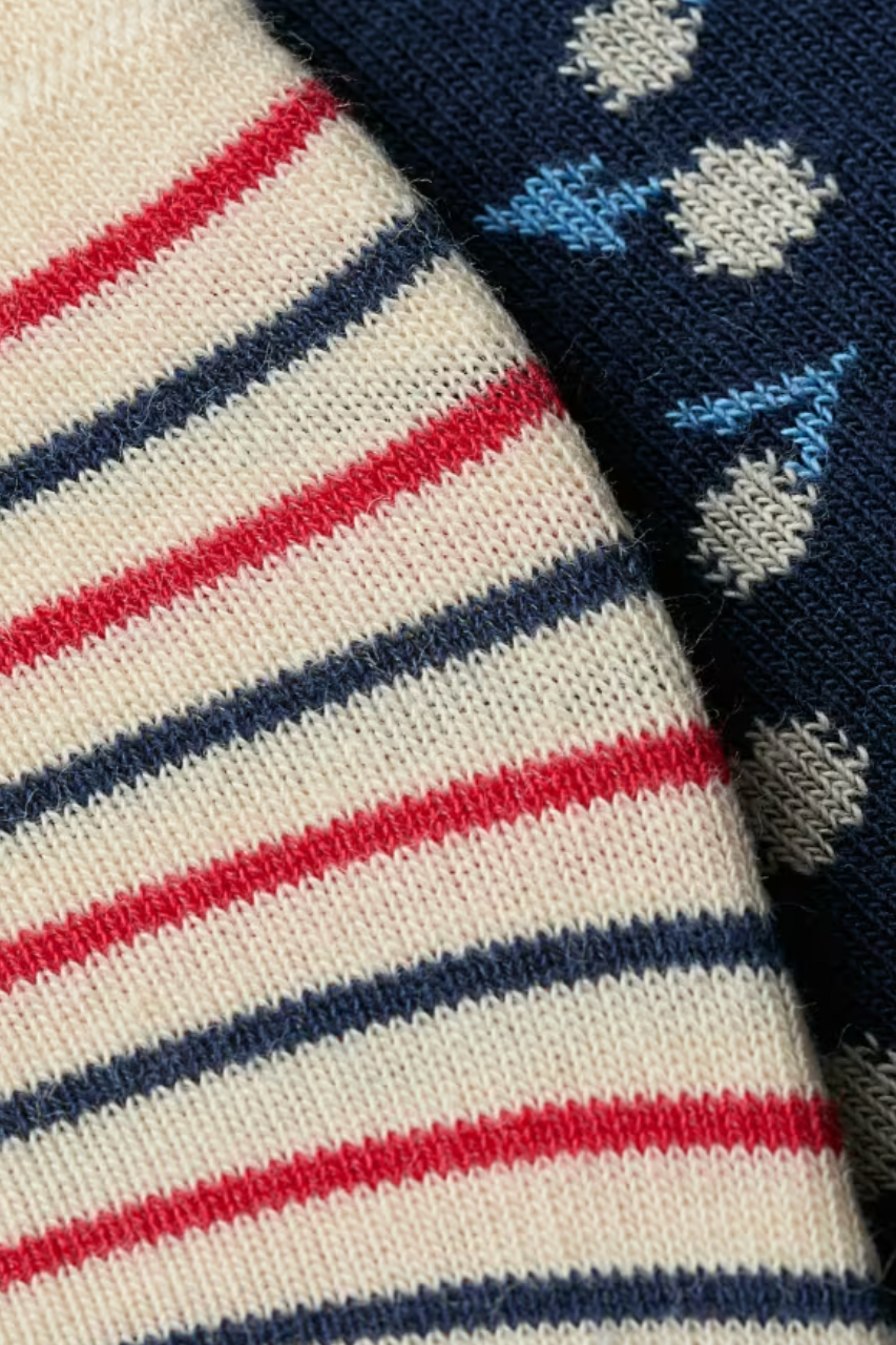 Close-up of soft organic cotton fabric featuring red and blue striped patterns alongside a dark blue floral print.