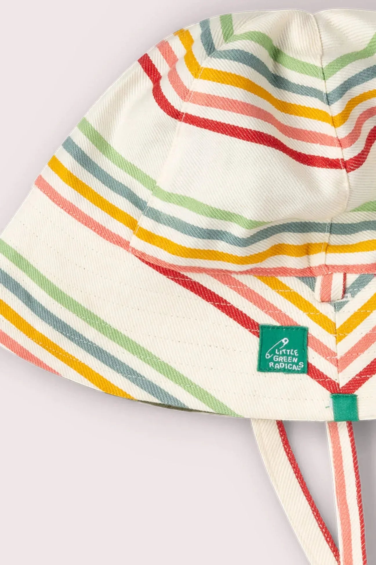 A Little Green Radicals white cotton bucket hat featuring colorful horizontal stripes and a chin strap.