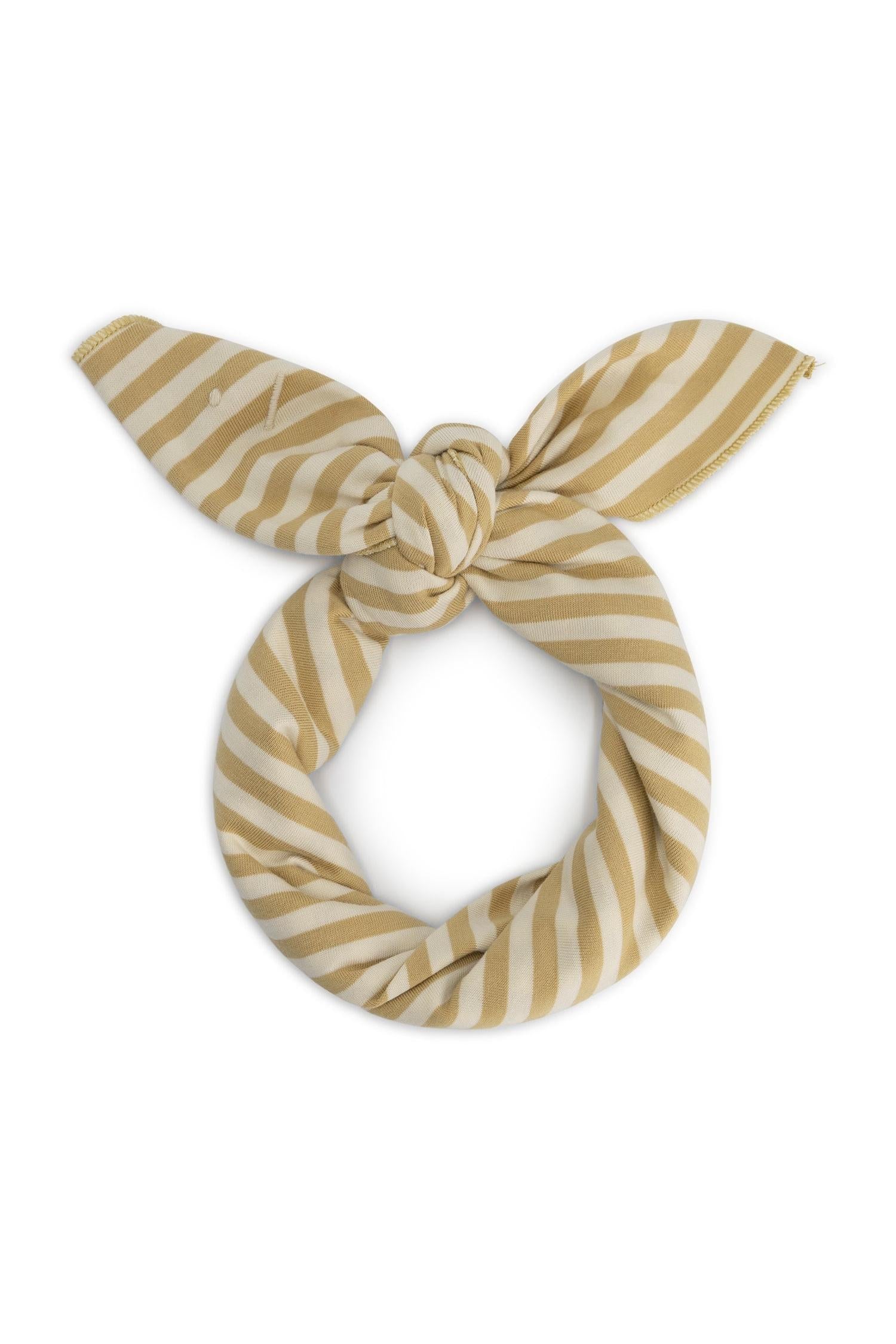 A fabric headband or hair tie styled in a knot, featuring alternating diagonal stripes of mustard yellow and cream on a solid white background.