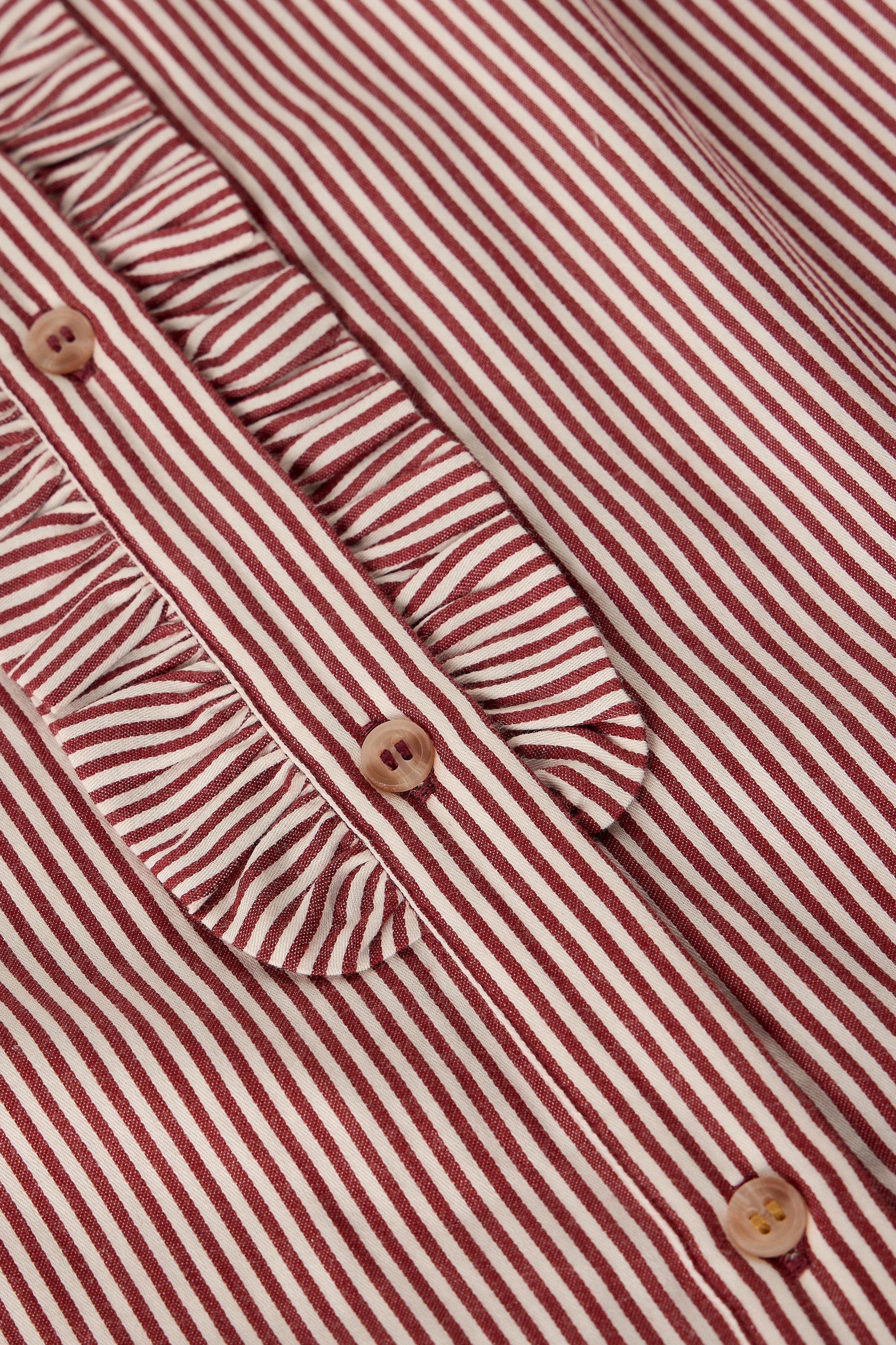 Close-up of a red and white striped blouse with a ruffled collar and decorative buttons.