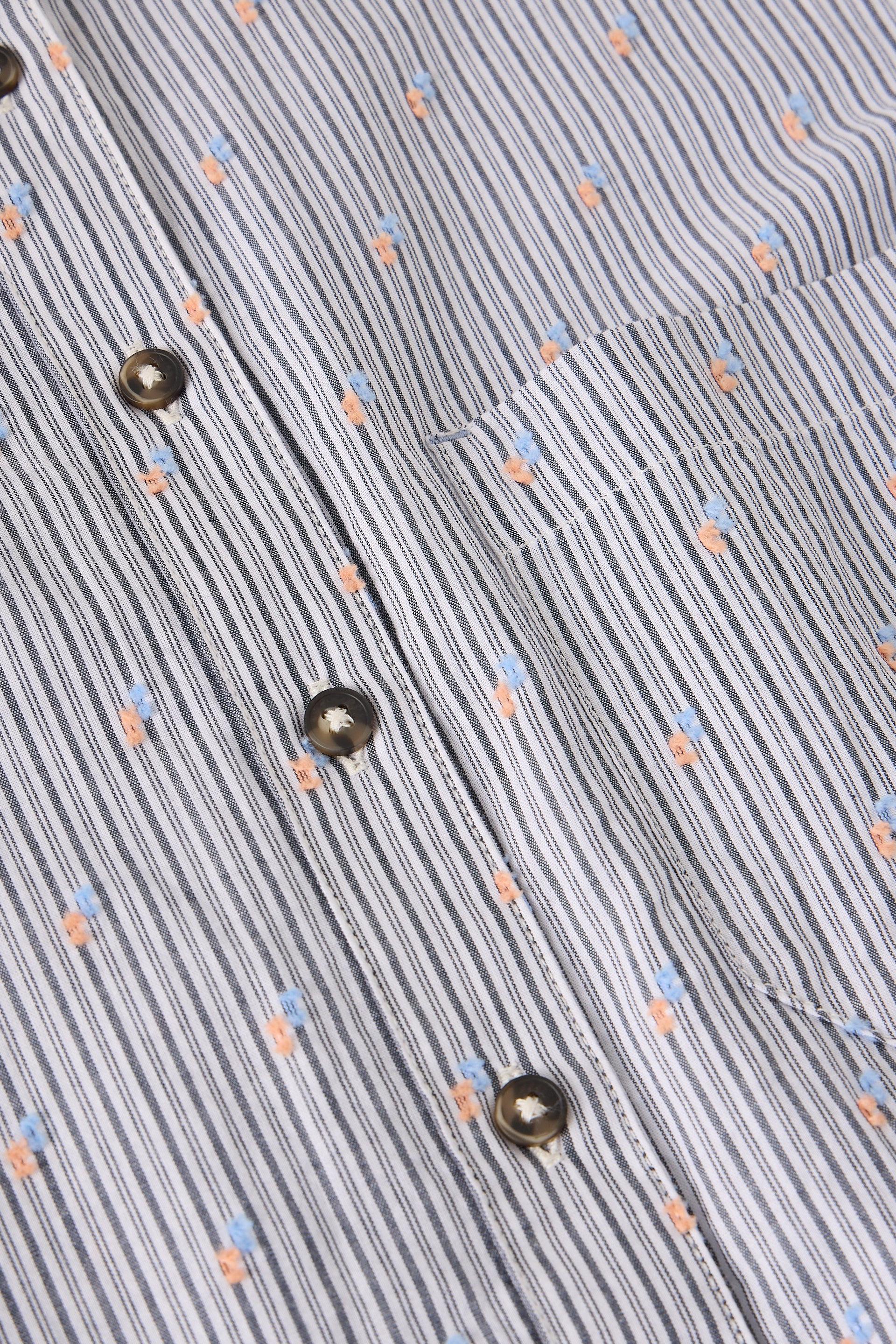 Close-up of a textured fabric with small buttons and colorful dots on a gray background