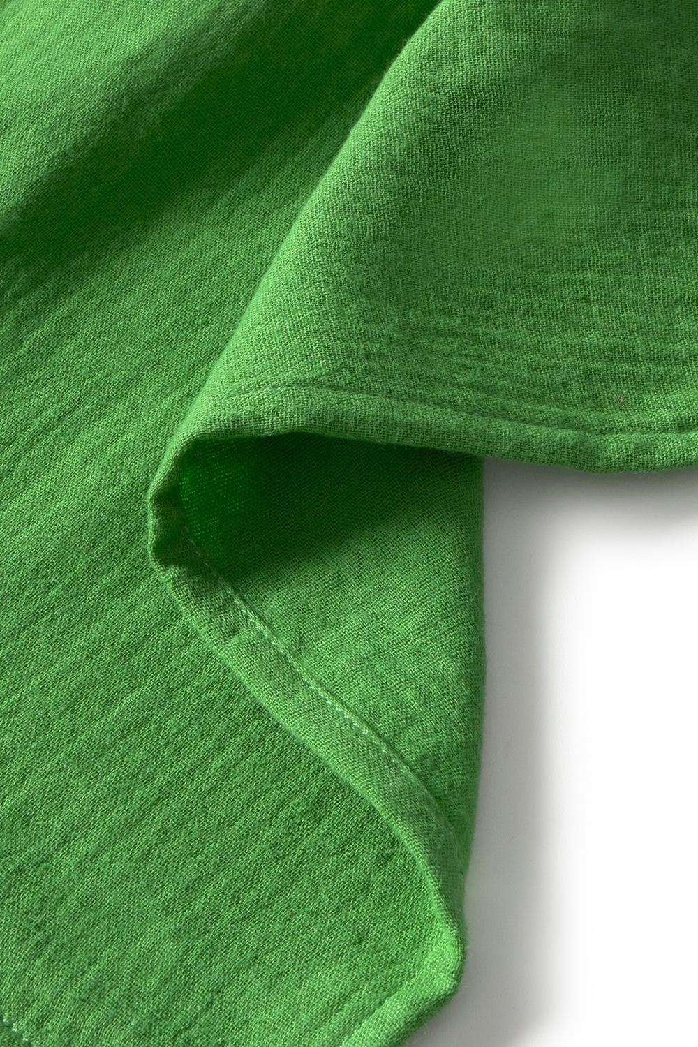 Close-up of green organic cotton fabric with a slight texture on a white background