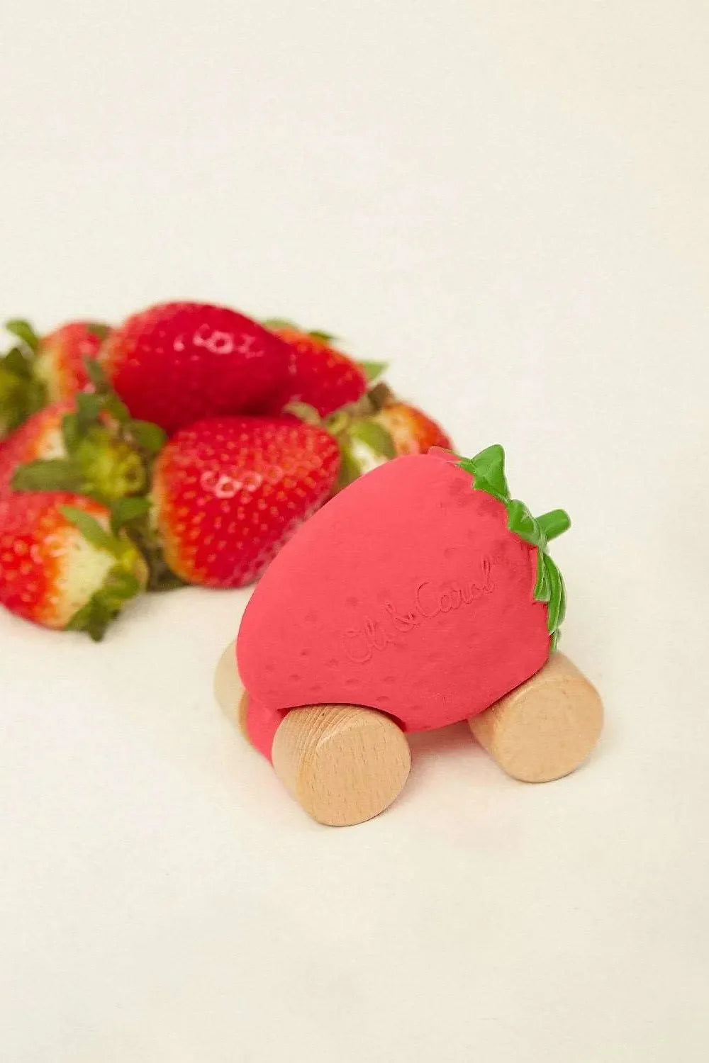 Handcrafted eco-friendly strawberry baby car toy beside strawberries.