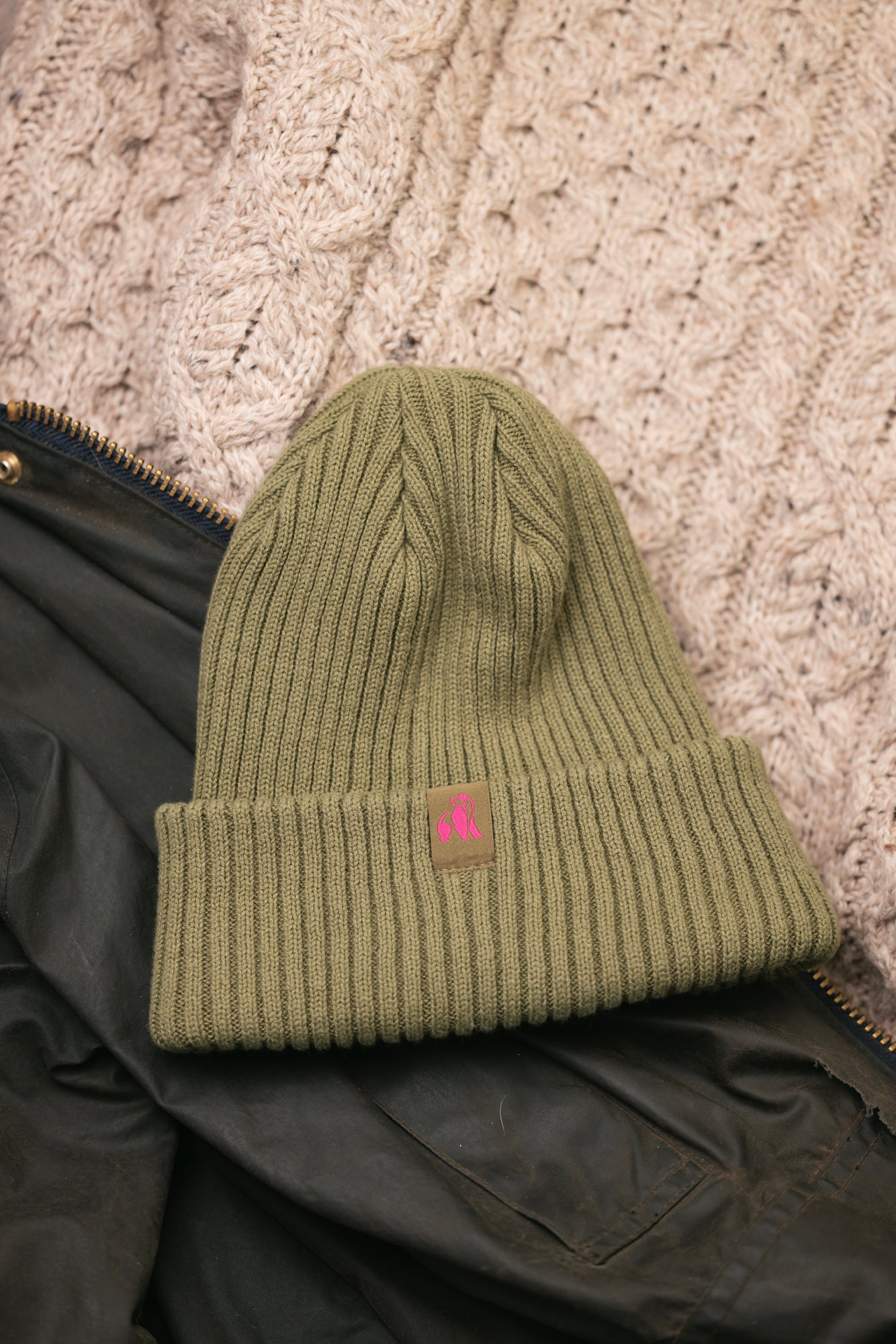 Green knit beanie with a logo on a textured surface