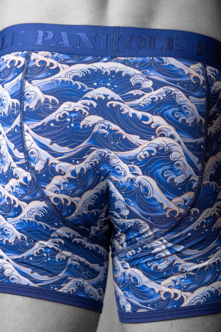 Rear view of a man wearing blue sea theme bamboo boxers with wave patterns by Swole Panda.