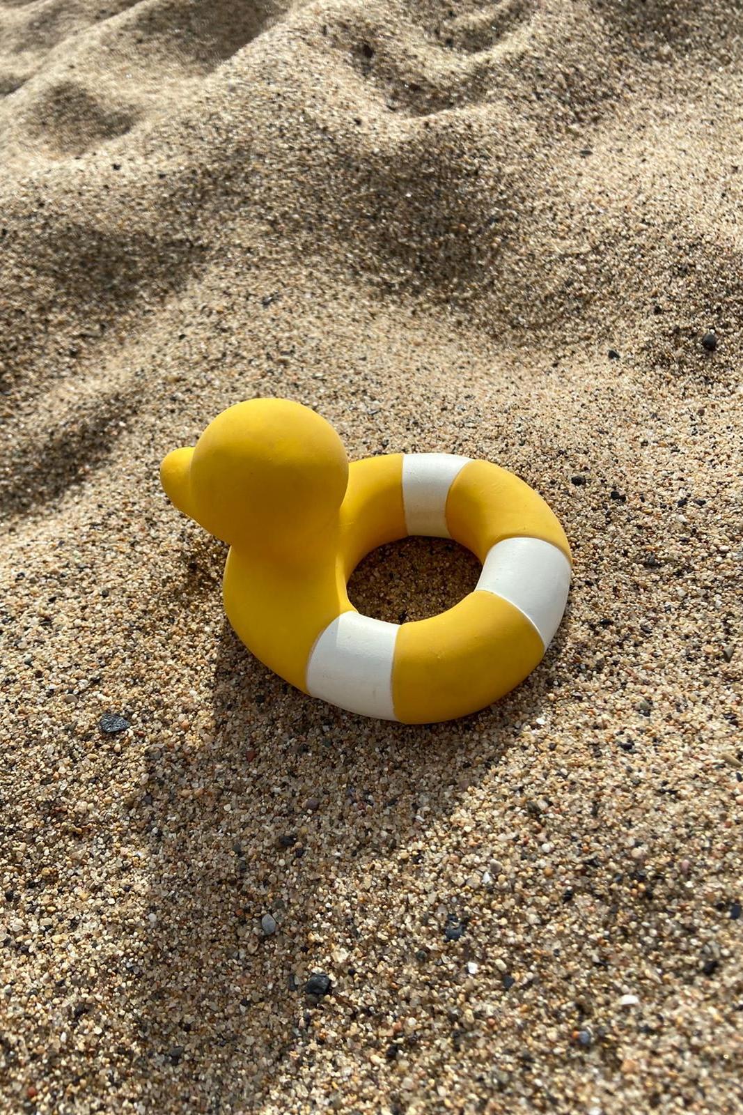 Natural rubber teether and bath toy on sandy beach