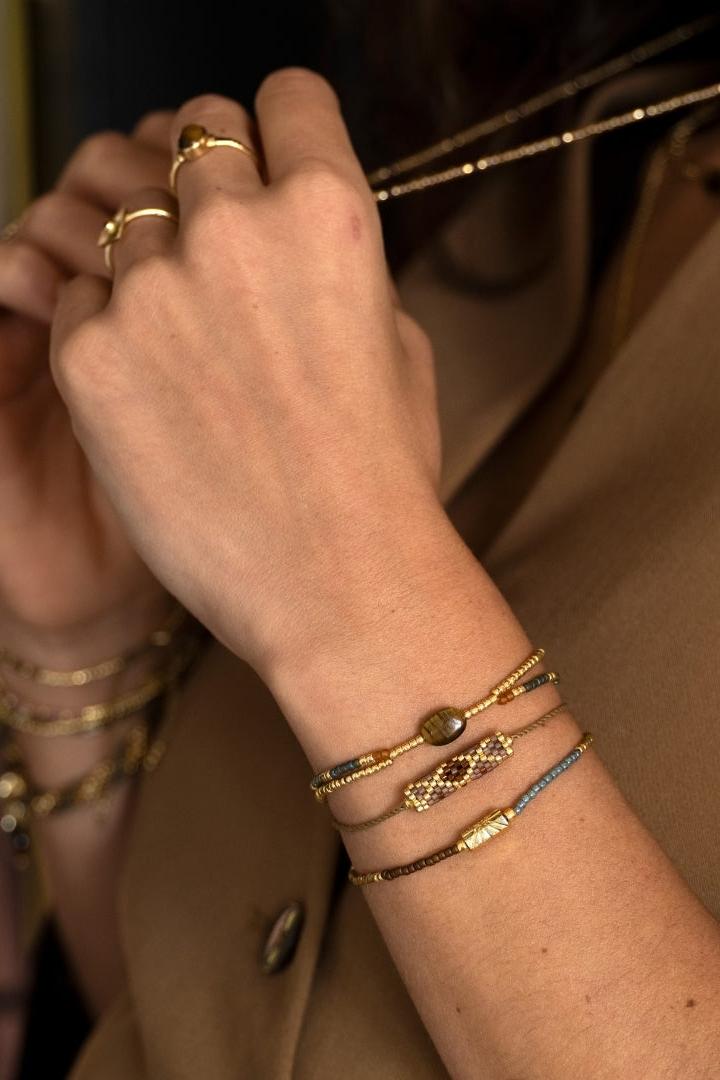 A woman wearing elegant tiger eye gemstone bracelets and stacked rings.