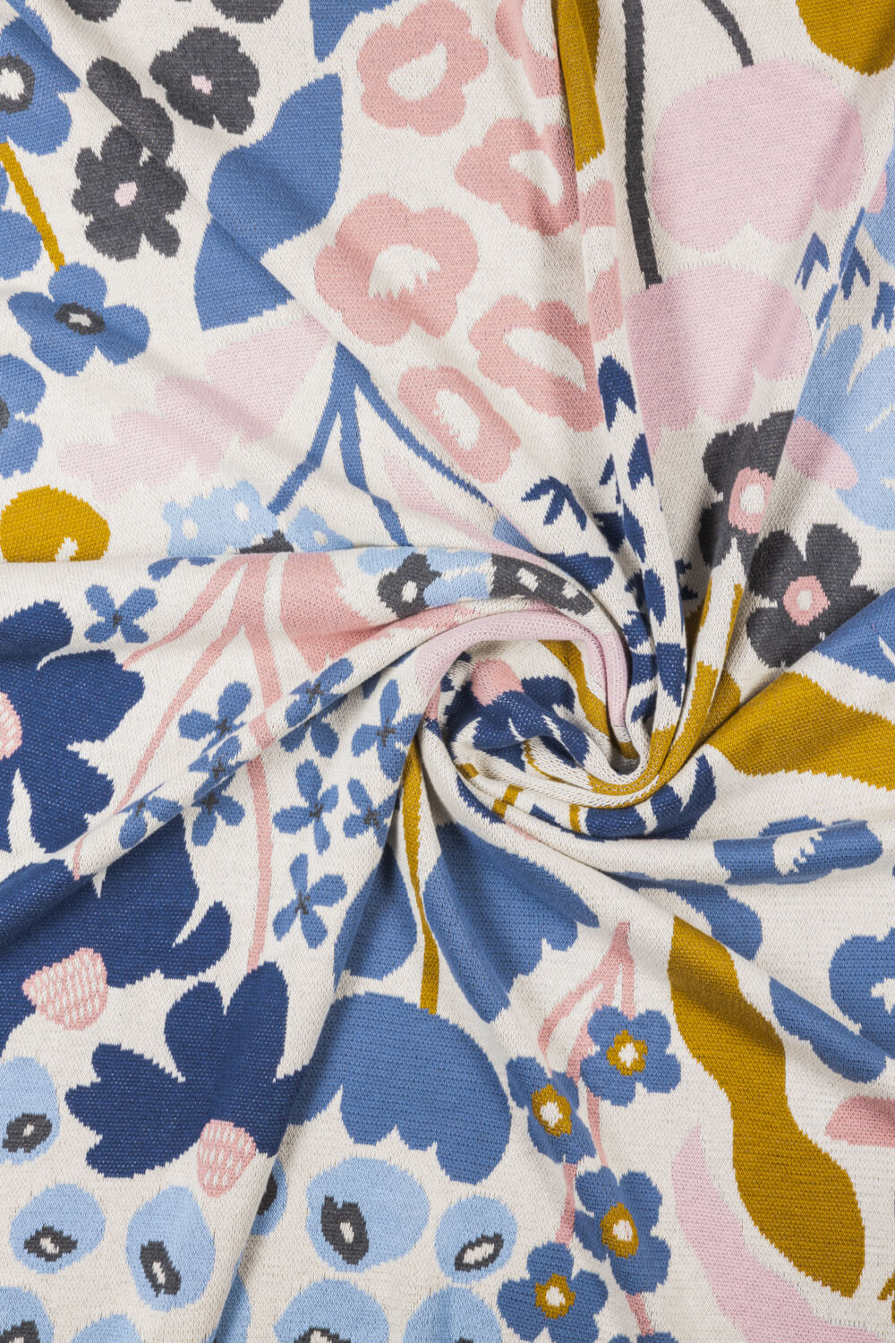 Close up of a patterned organic cotton knit blanket with blue, pink, and mustard flower designs.