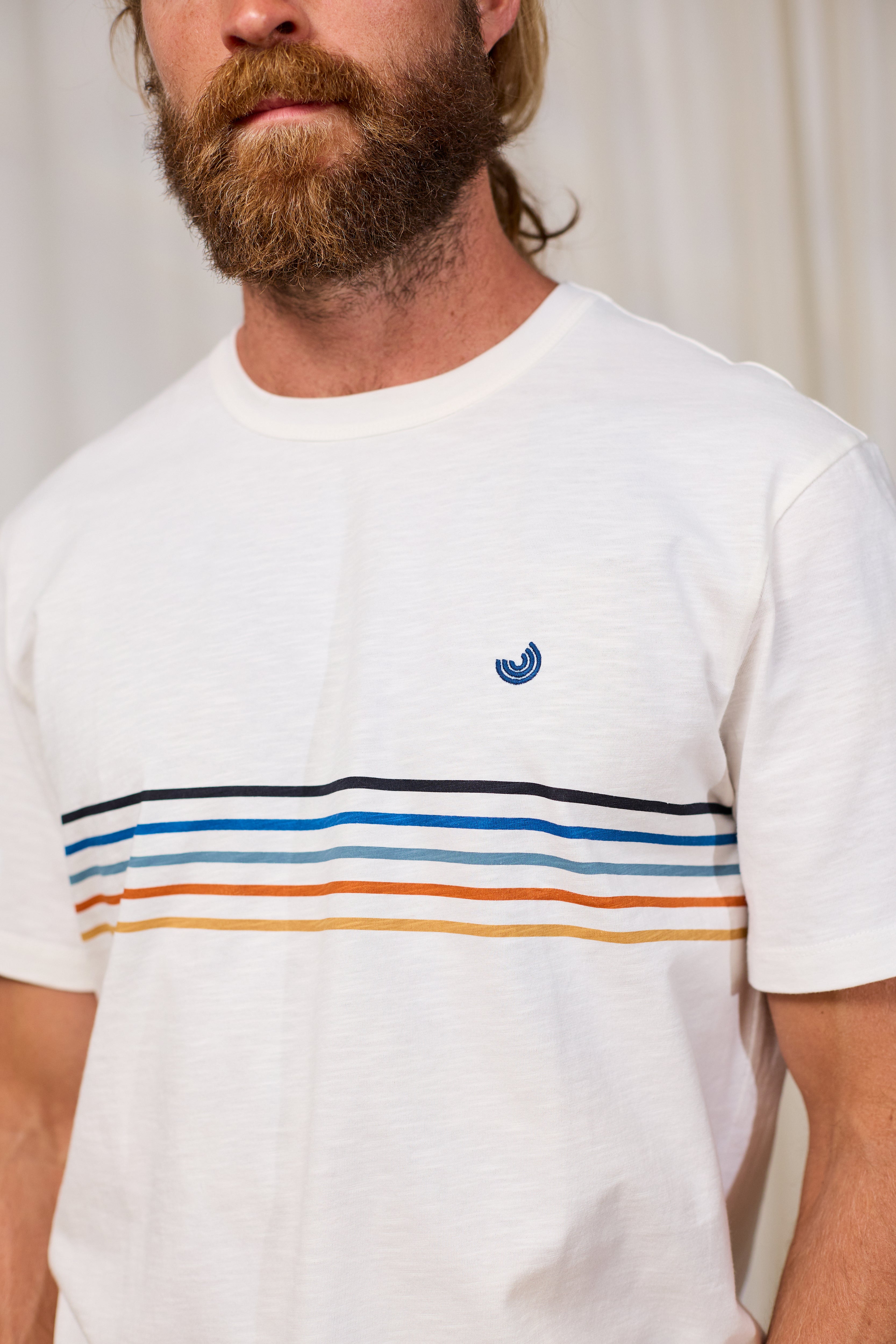 Man wearing a white TWOTHIRDS t-shirt with colorful stripes and a small logo.
