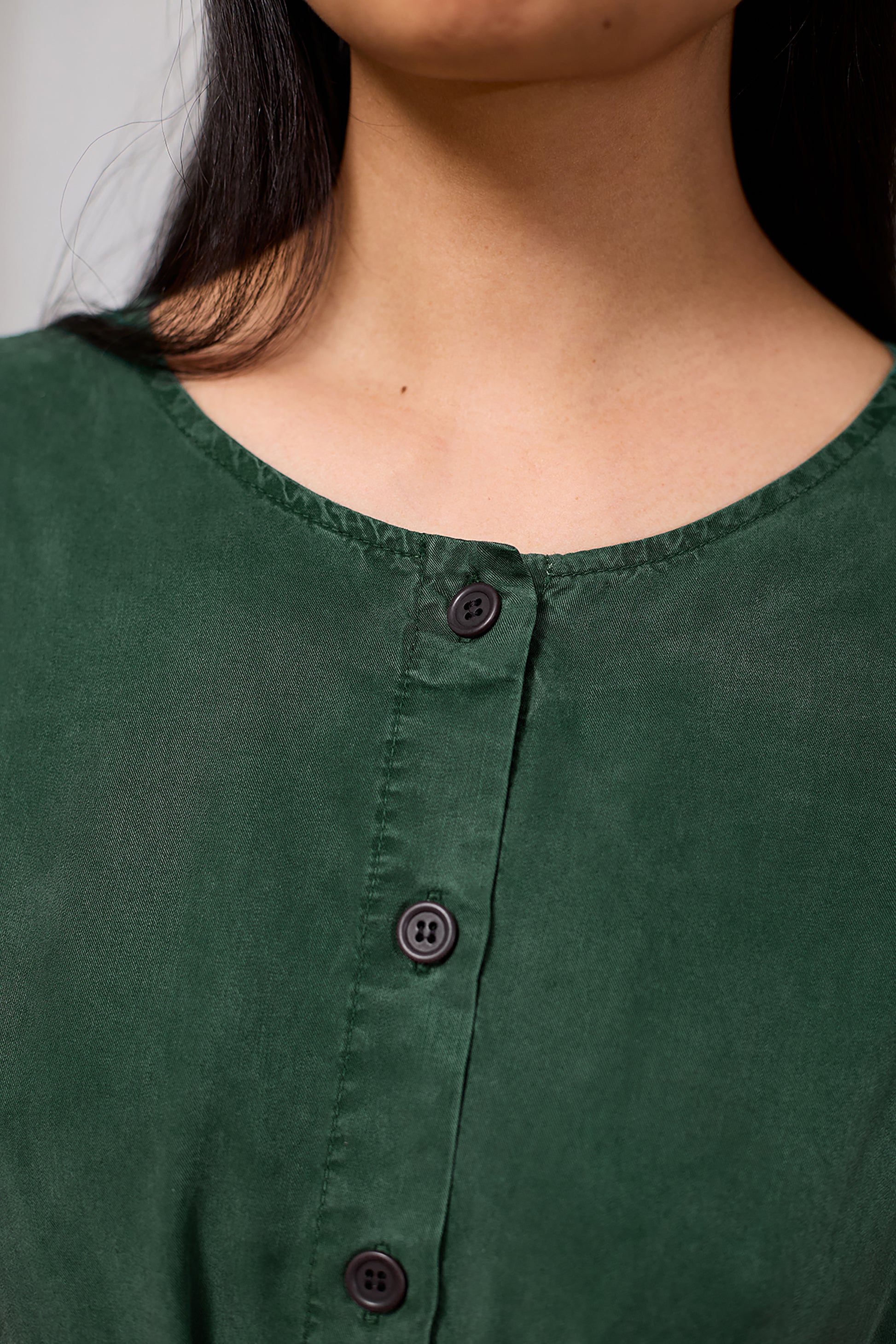 Close-up of a green dress with buttons worn by a model