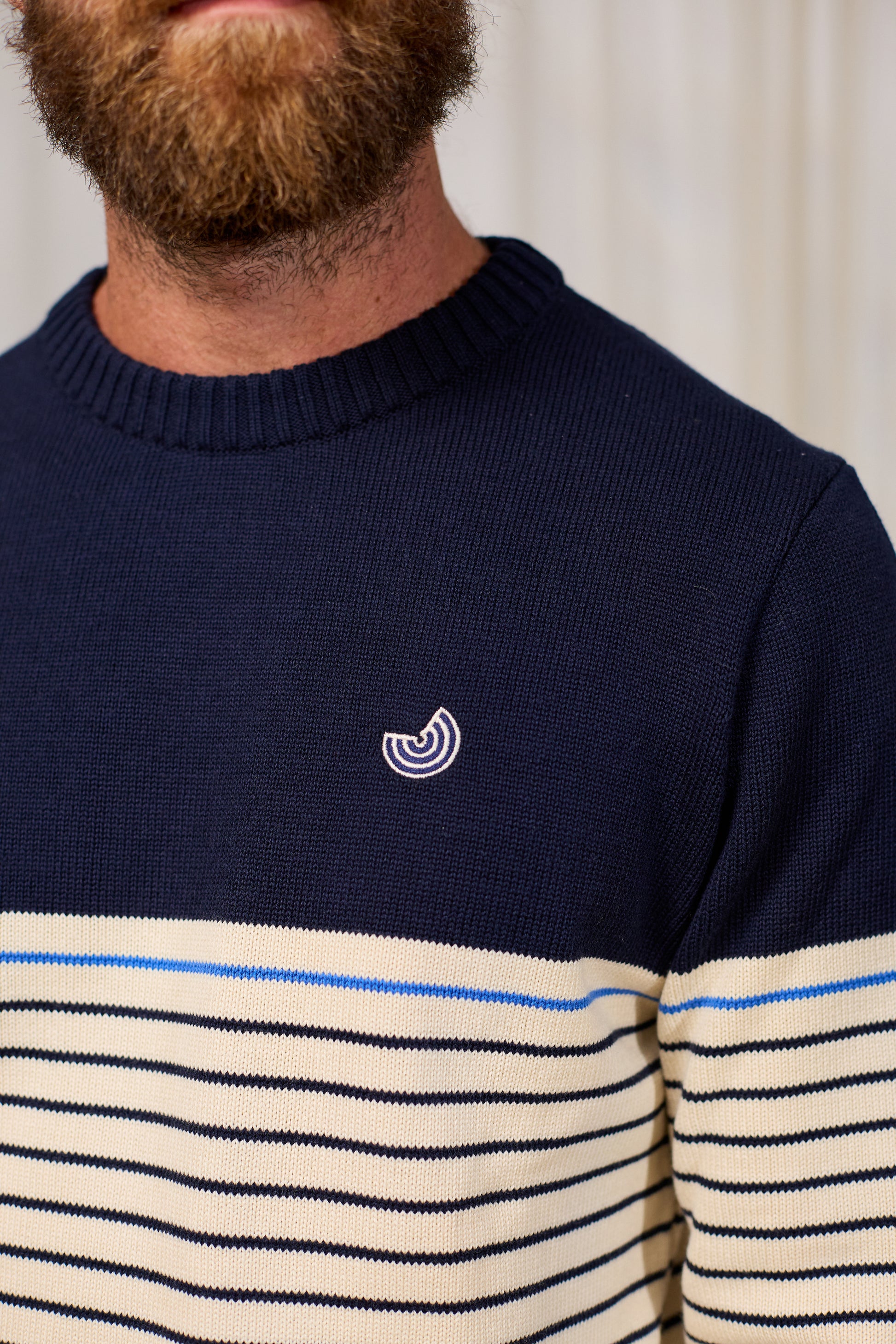 Navy organic cotton sweater with striped pattern worn by a person, featuring a small logo on the chest.