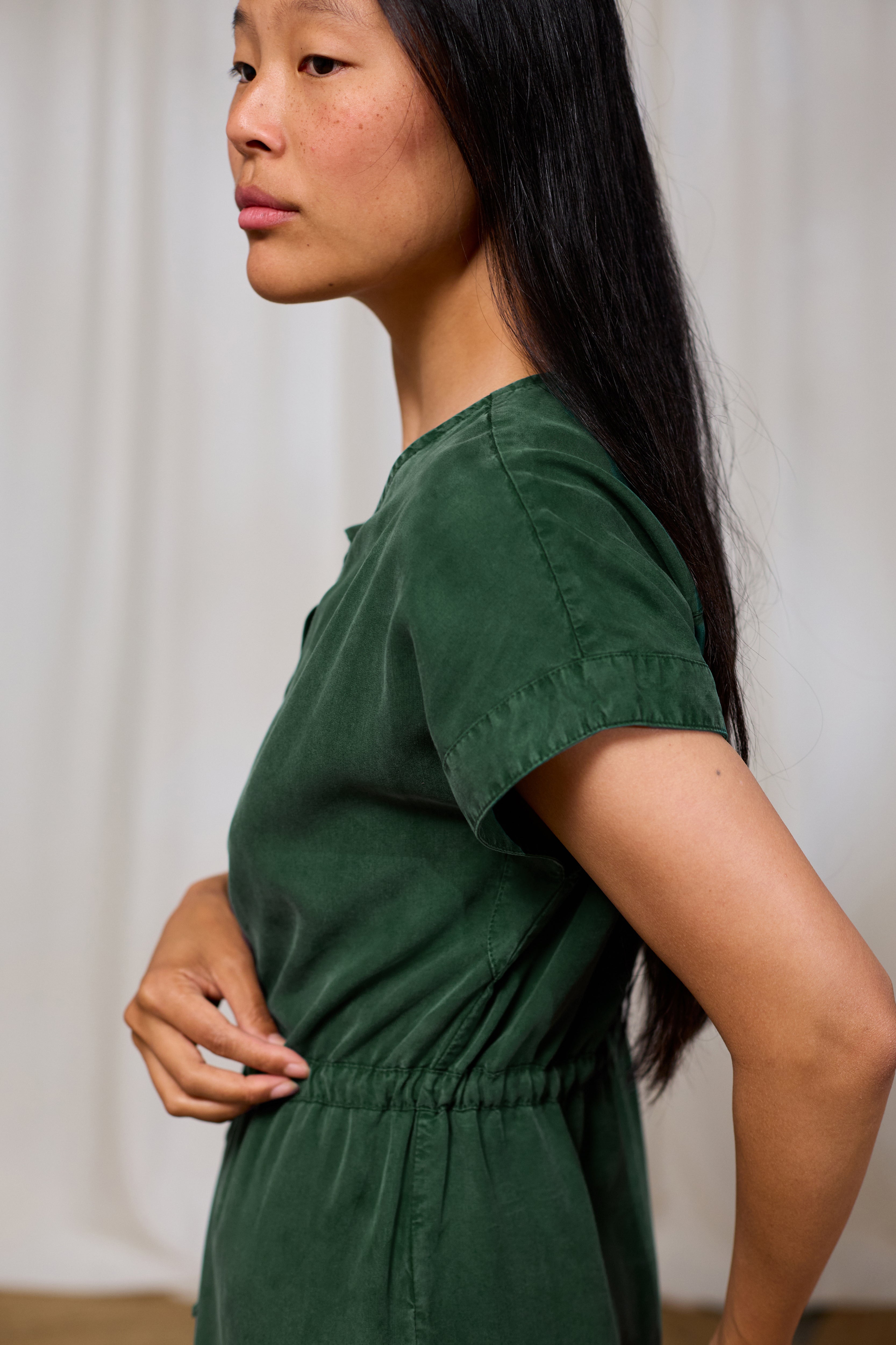 Woman wearing a green TWOTHIRDS dress against a plain background