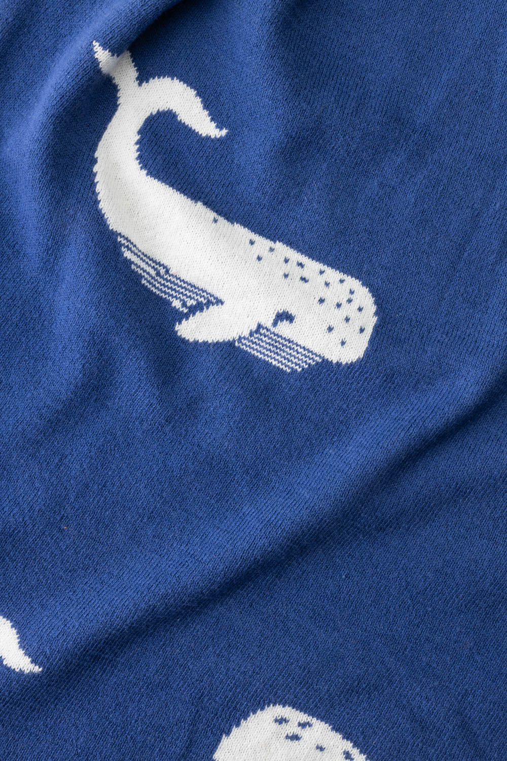 Soft blue organic cotton baby blanket with a repeating white whale pattern.