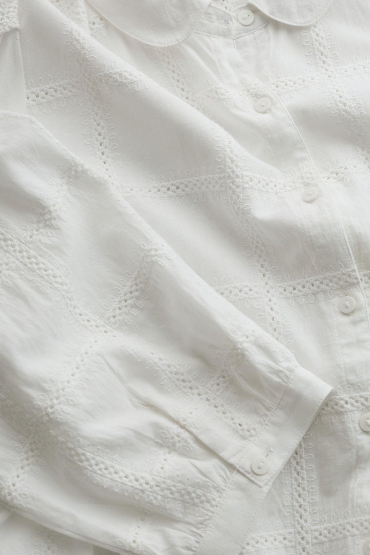 Close-up of a white women's shirt featuring delicate embroidery and organic cotton fabric.