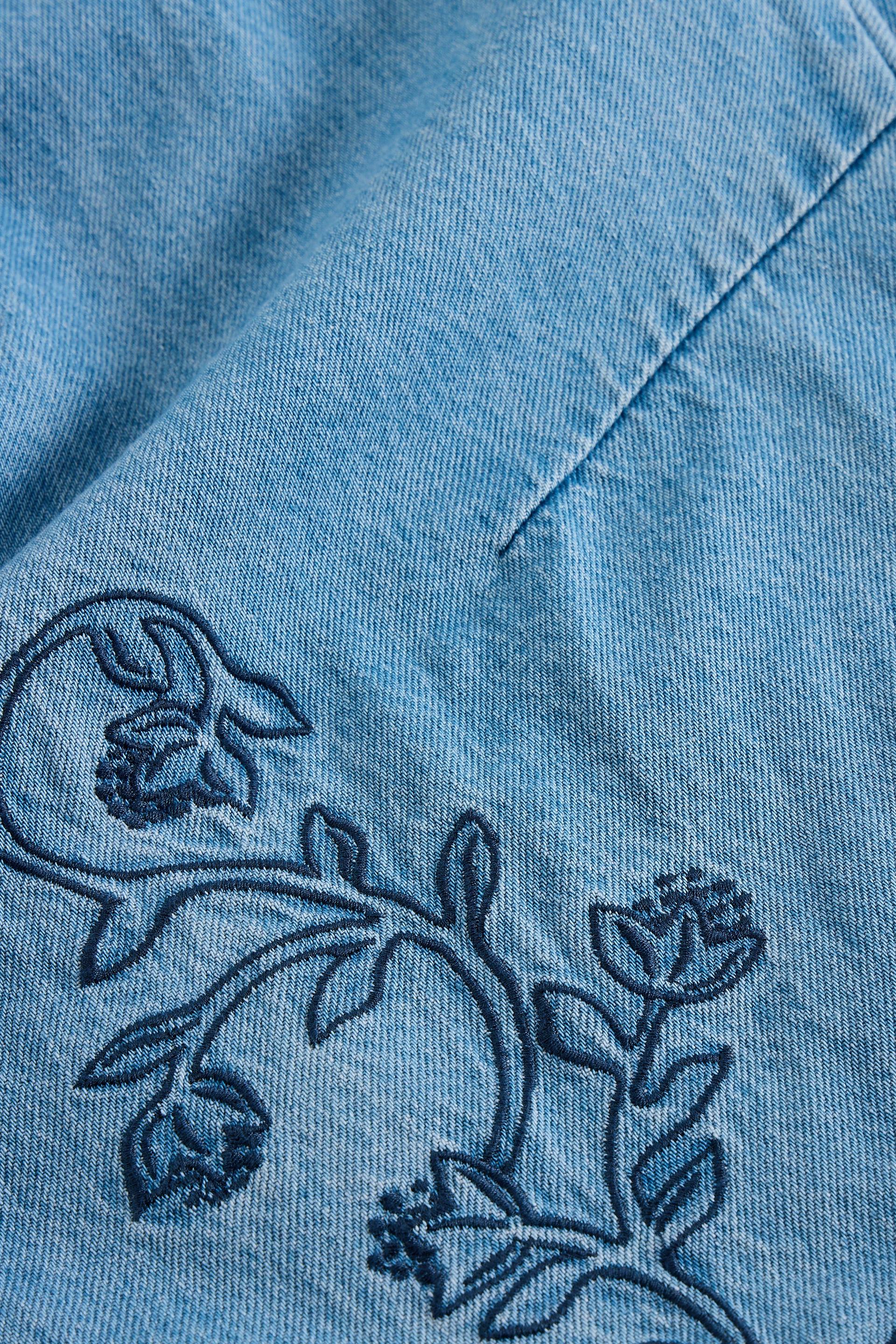 Close-up of blue jeans with floral embroidery