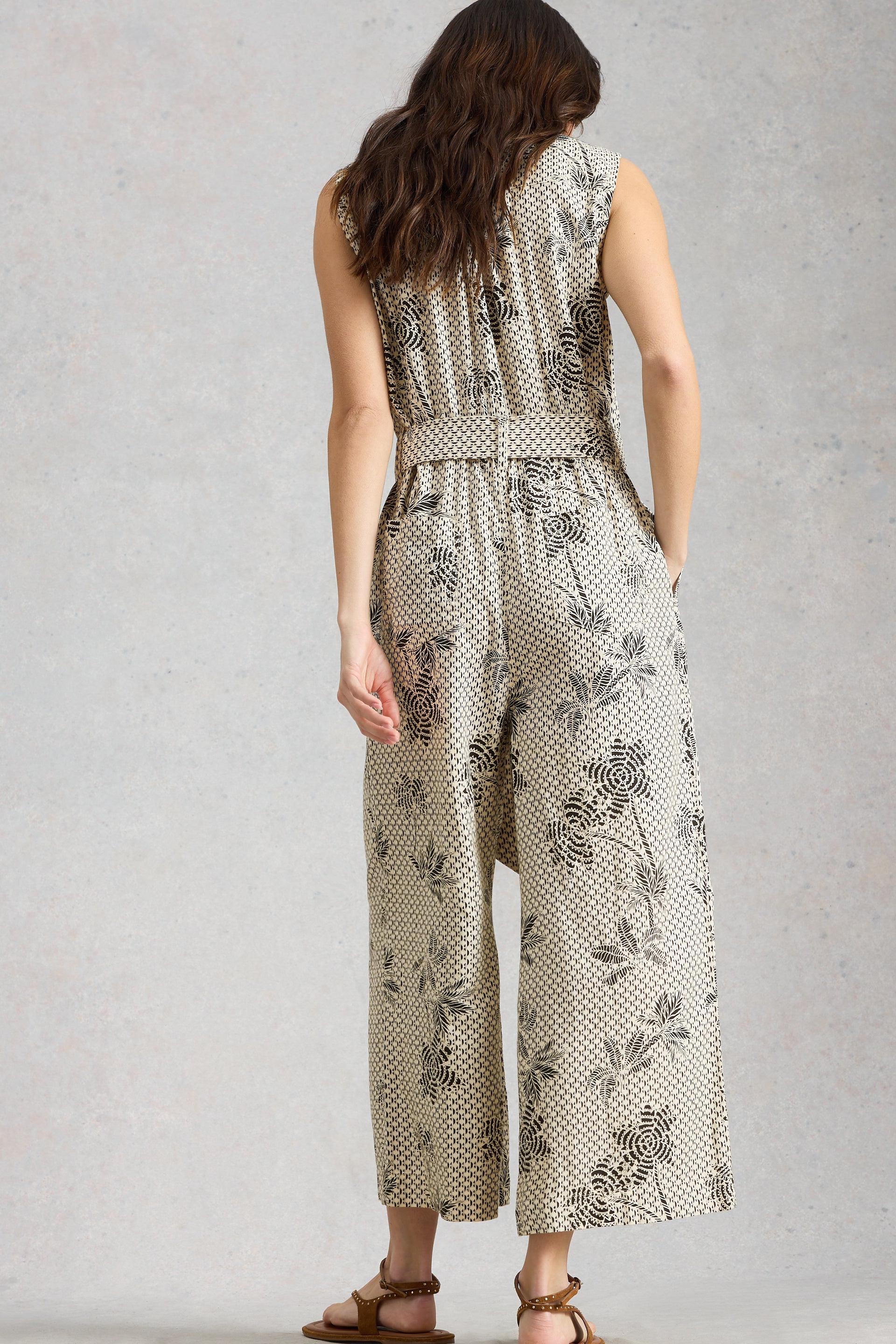 Woman wearing a floral patterned jumpsuit on a plain background