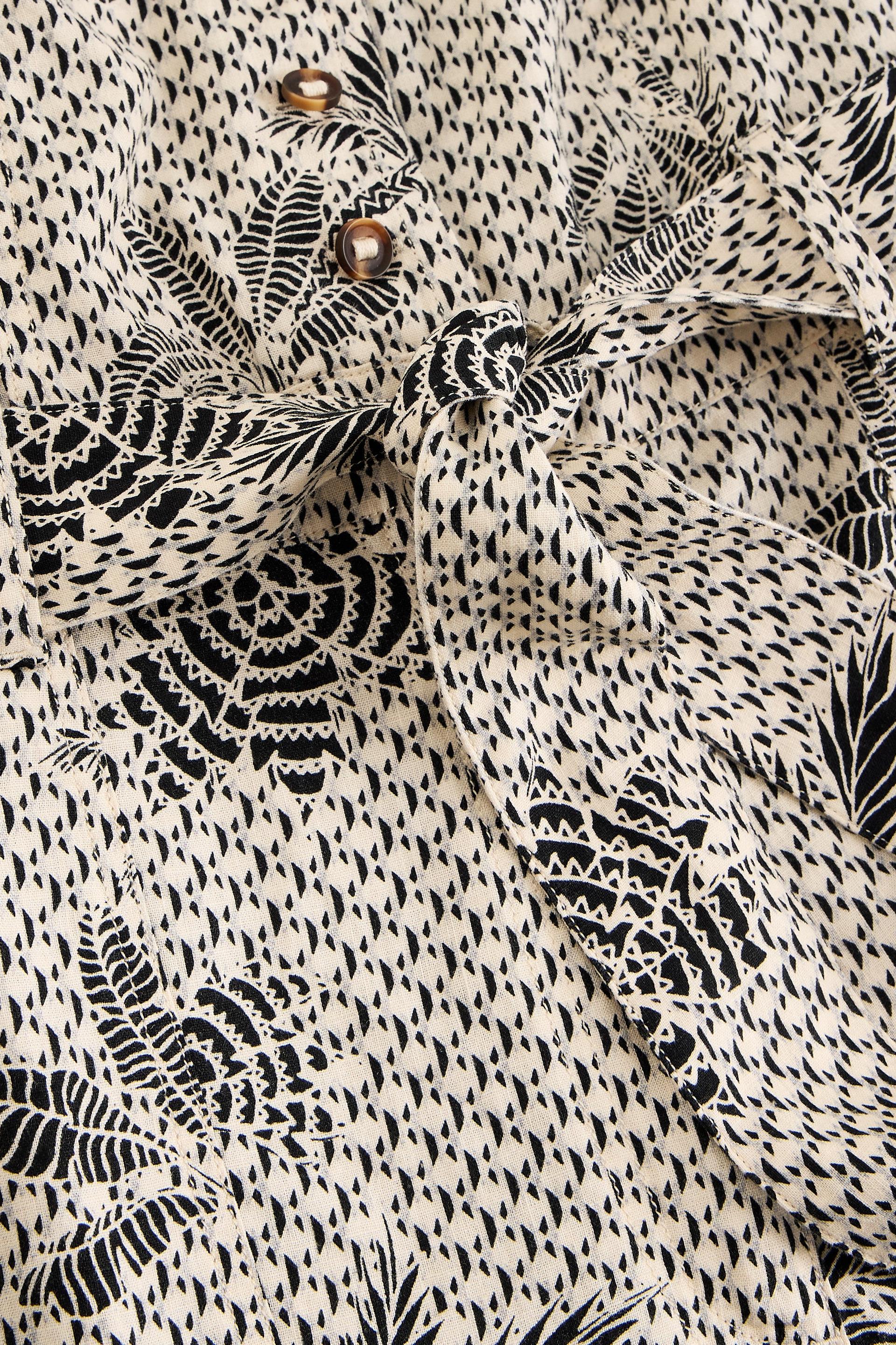 Close-up of a patterned jumpsuit with black and white design and belt detail