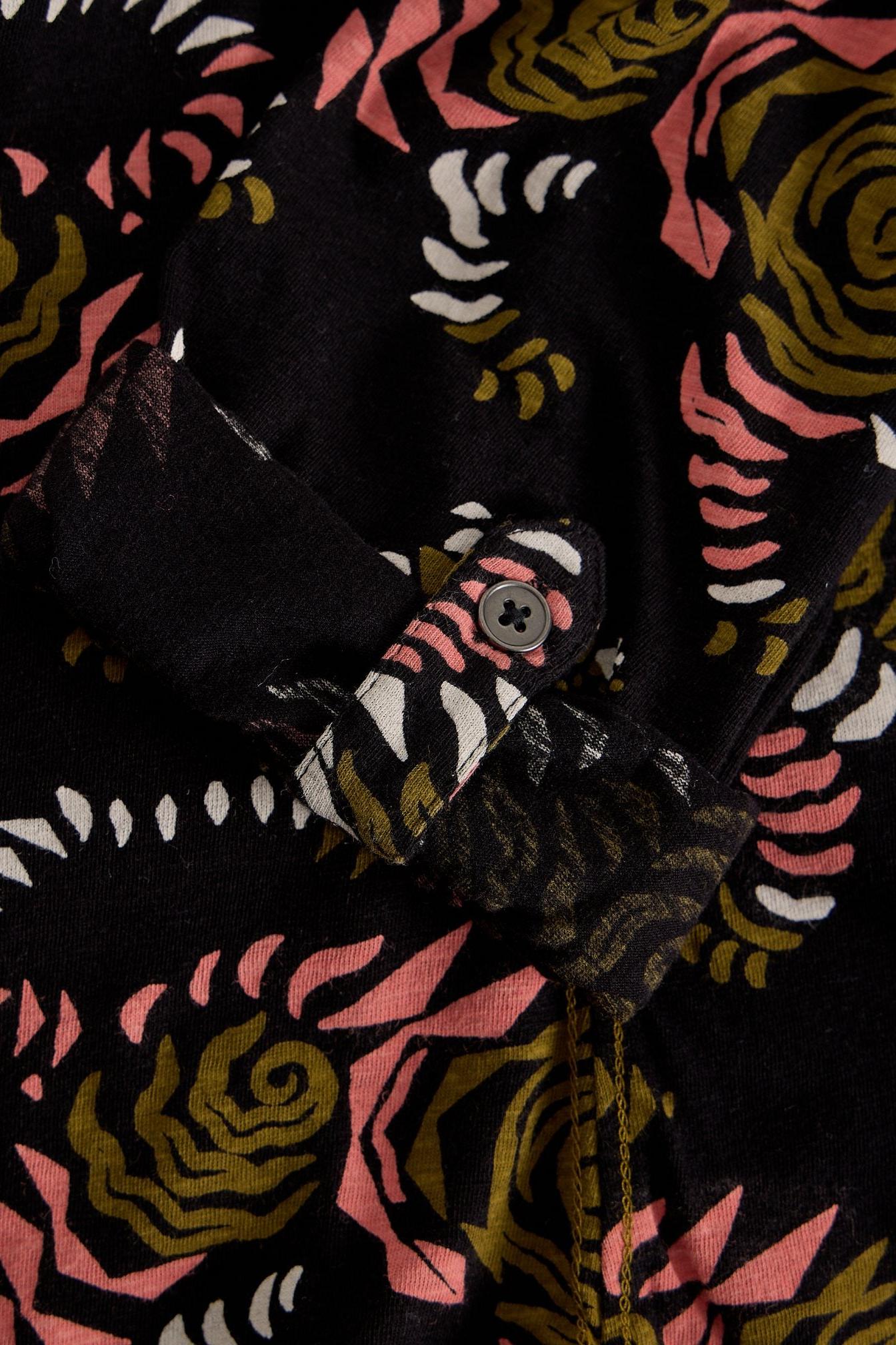 Close-up of a White Stuff black cotton shirt sleeve with floral print and a buttoned tab detail.