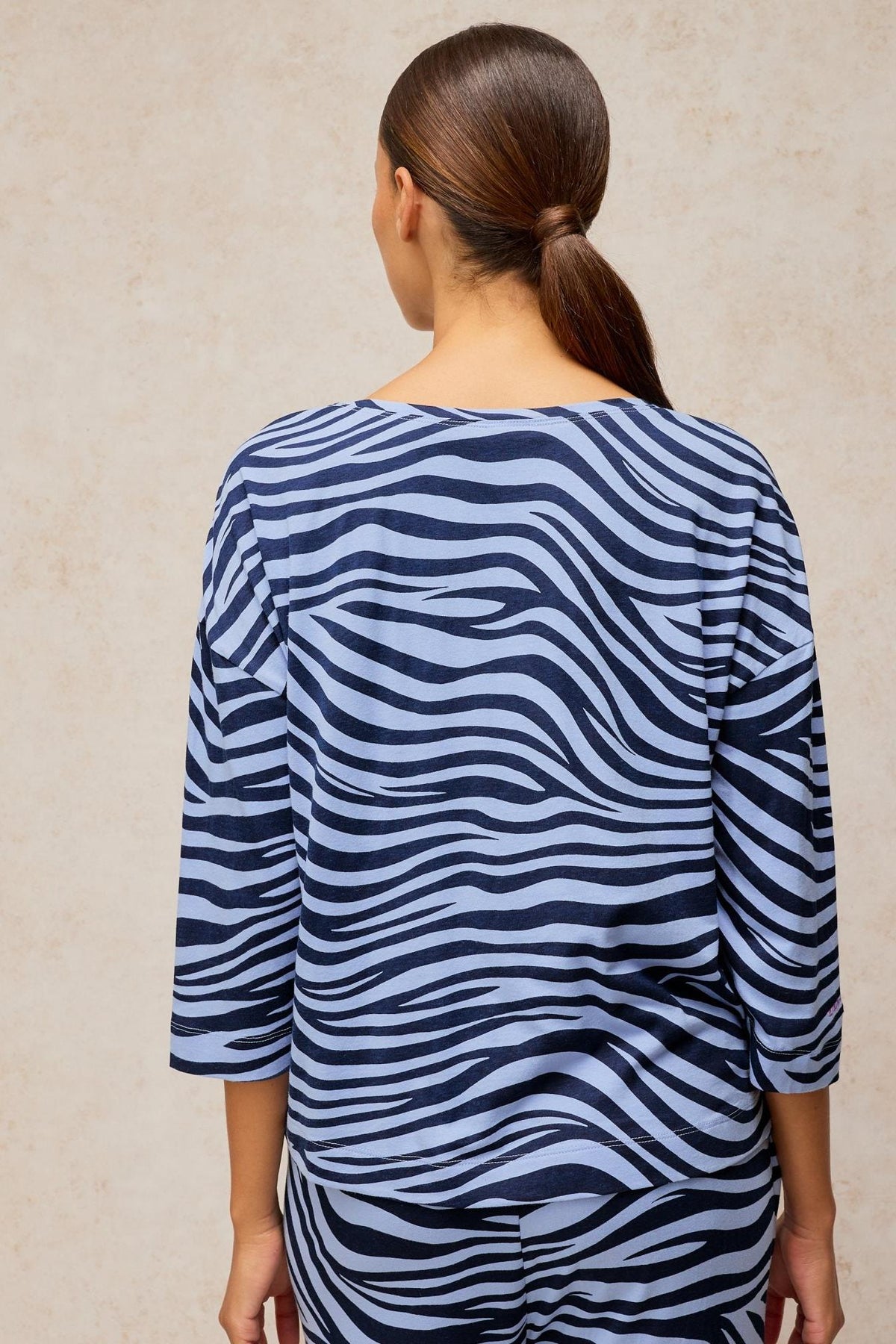 A woman seen from the back wearing a blue White Stuff animal print pyjama top.