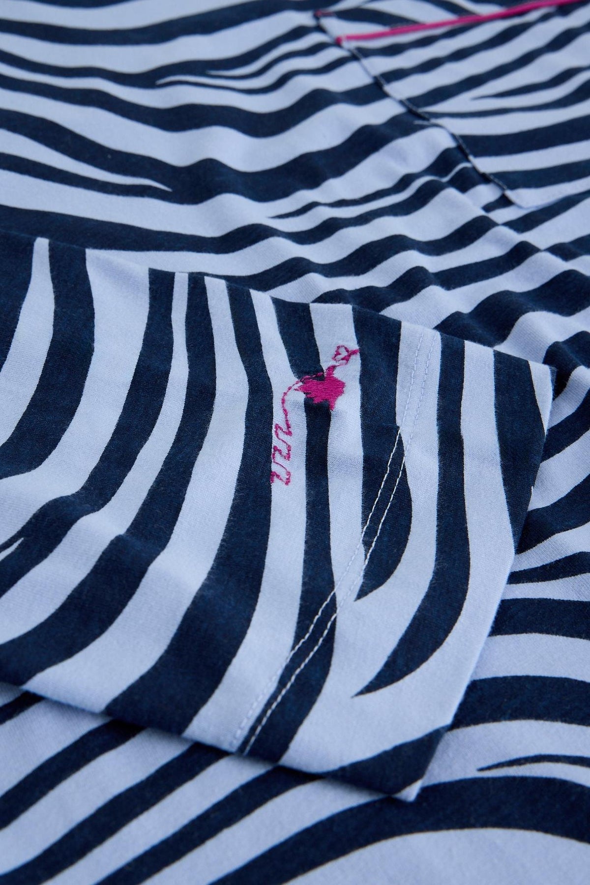 Close-up of a blue and white zebra print White Stuff pyjama top with pink embroidery on the sleeve.