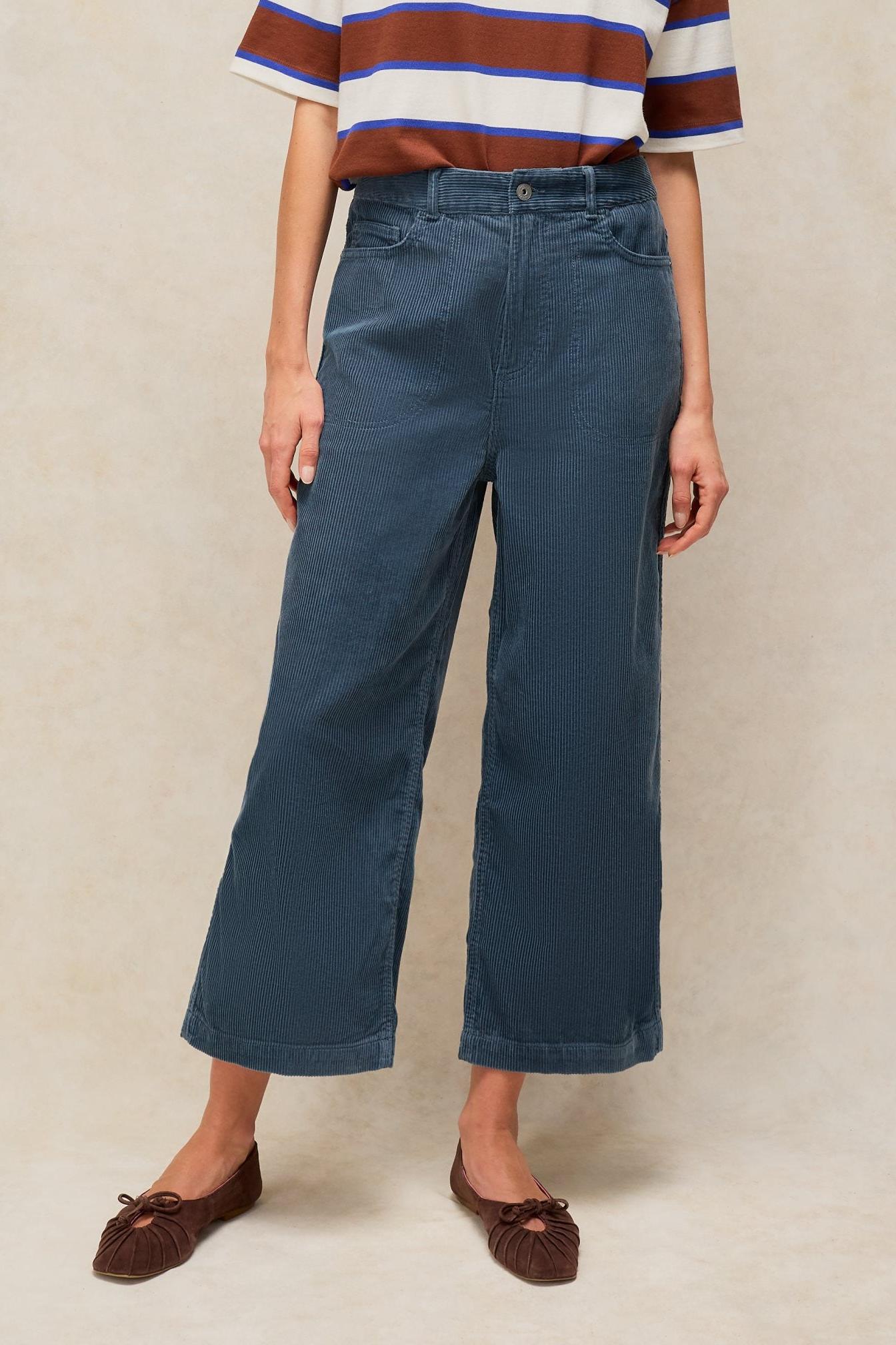 A woman wearing blue corduroy wide leg cropped trousers paired with a striped t-shirt.