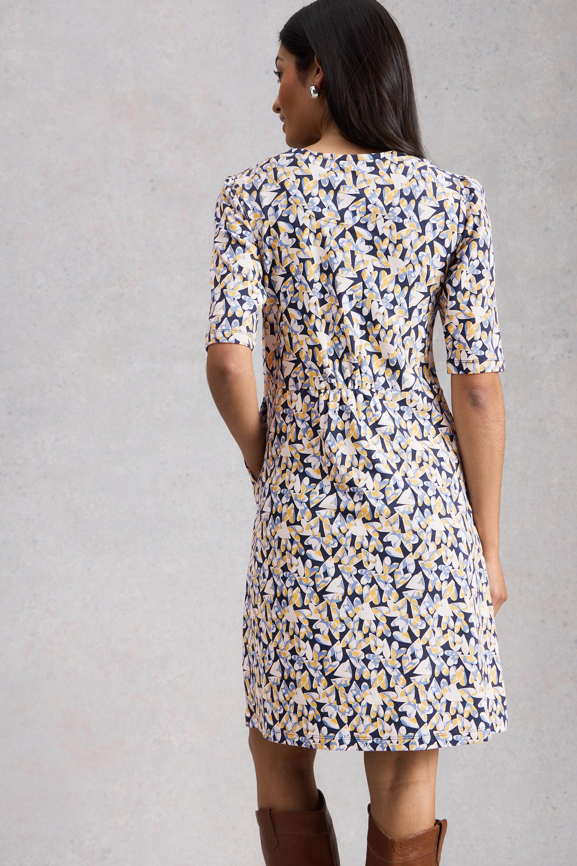Woman wearing a floral organic cotton dress against a gray background