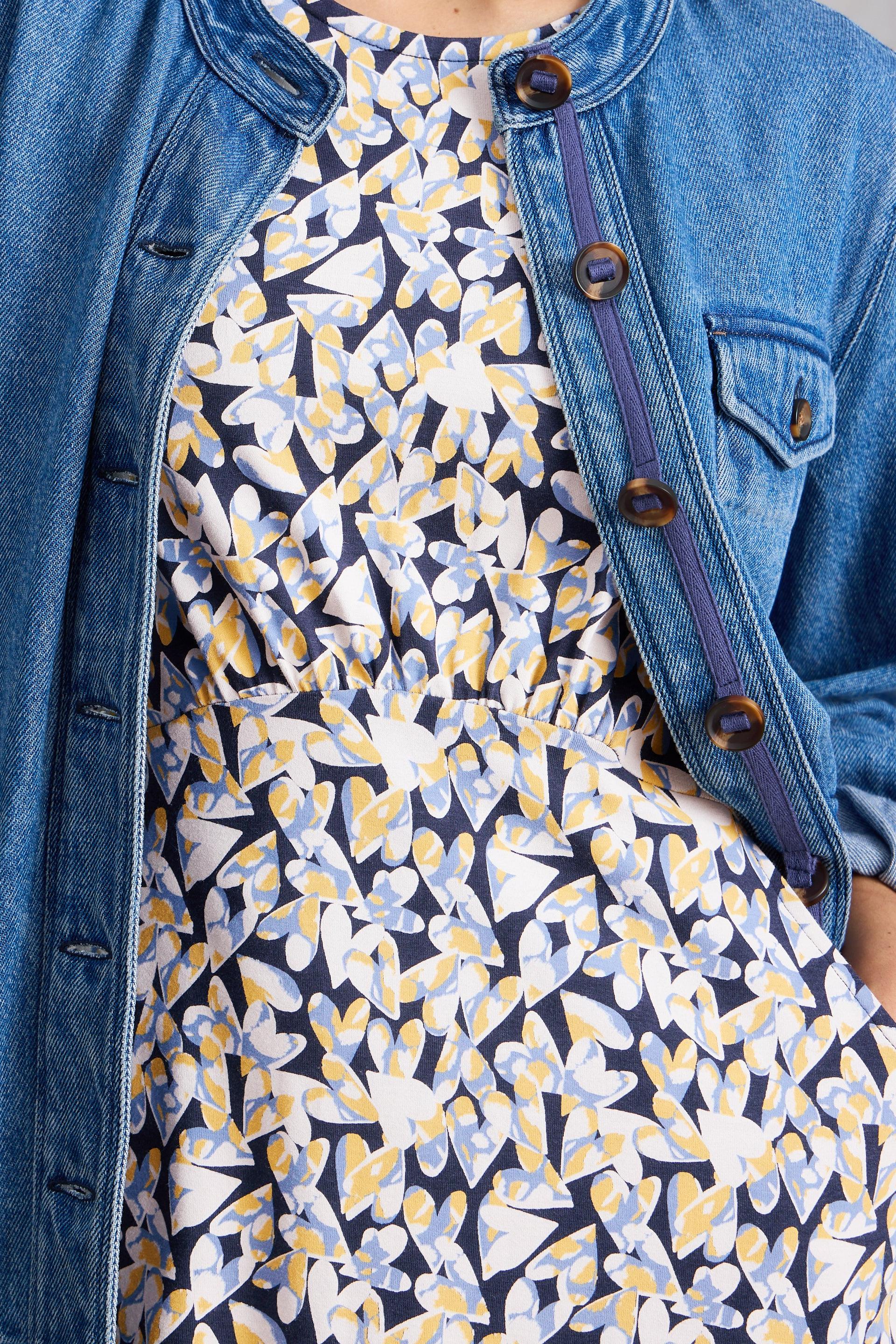 Woman wearing a floral organic cotton dress with a denim jacket