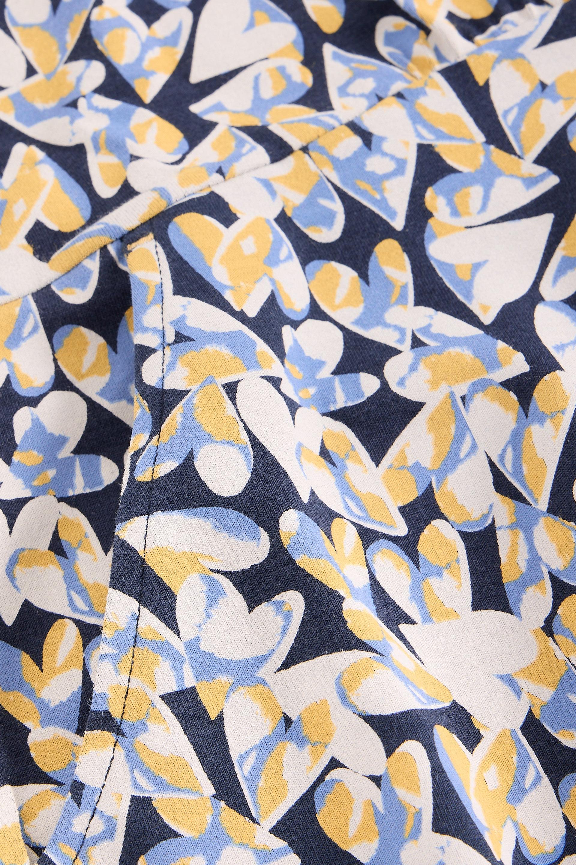 Close-up of organic cotton fabric with a heart pattern in blue, yellow, and white on a dark background.