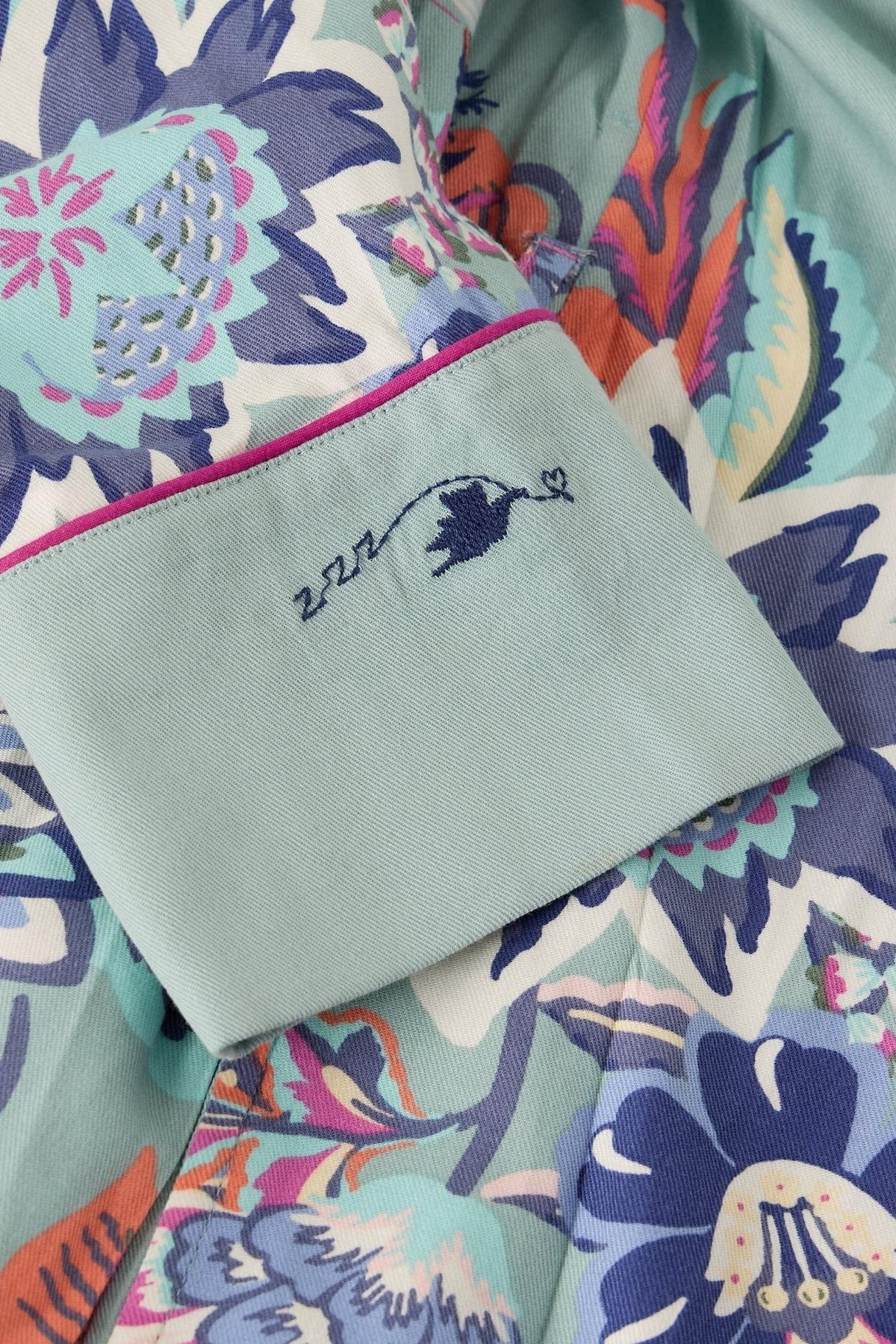 Close up of a White Stuff women's dressing gown sleeve cuff featuring a blue floral pattern and sleep embroidery.