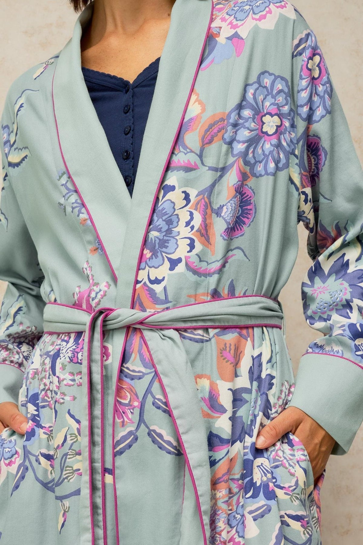 A person wearing a White Stuff blue floral patterned dressing gown with pink piping.