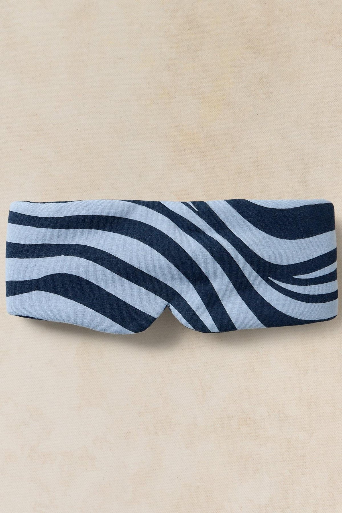 White Stuff women's sleep mask with blue and light blue zebra stripe pattern on a neutral background