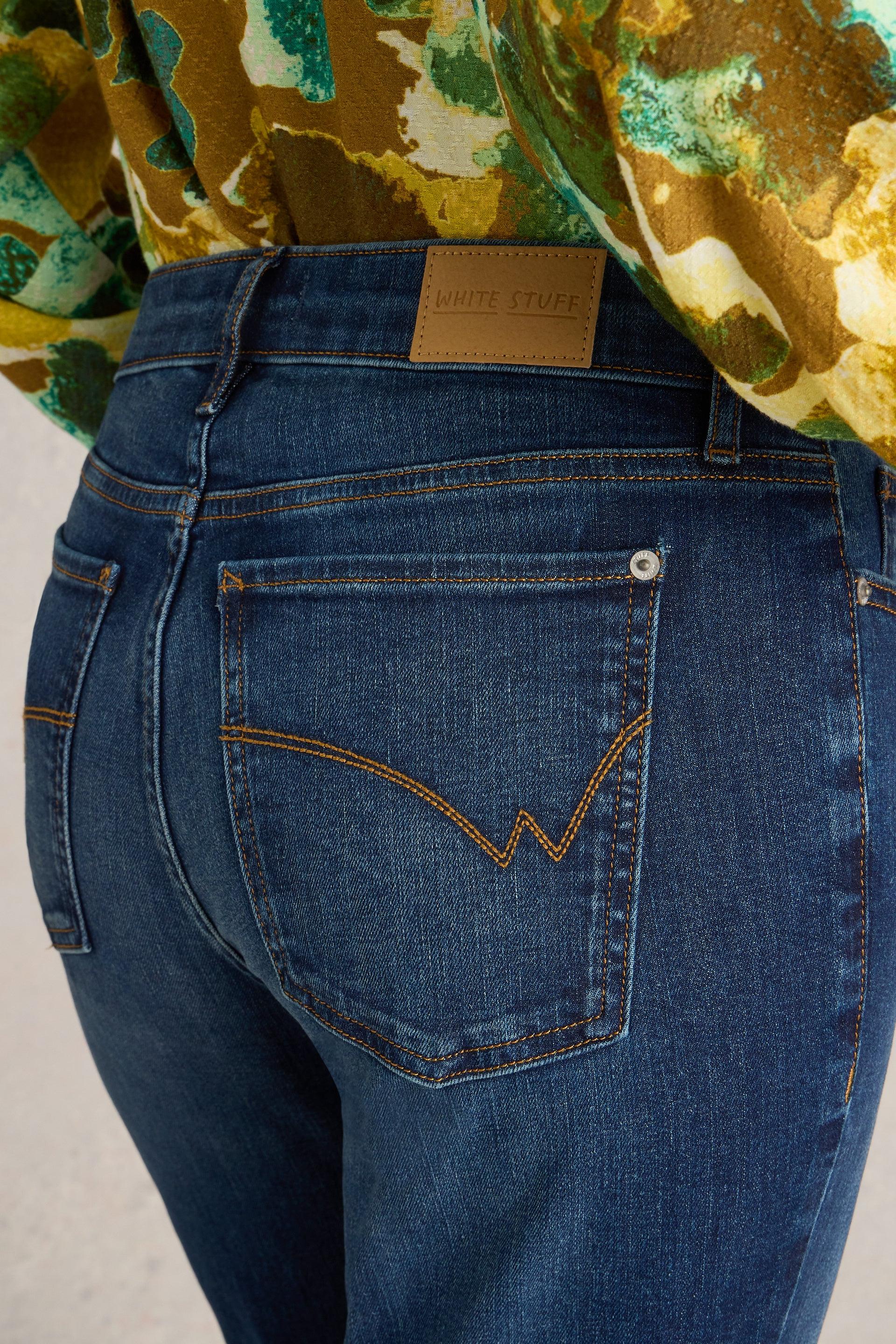 Close-up back view of White Stuff bootcut jeans with a branded leather patch and detailed stitching on the pockets.
