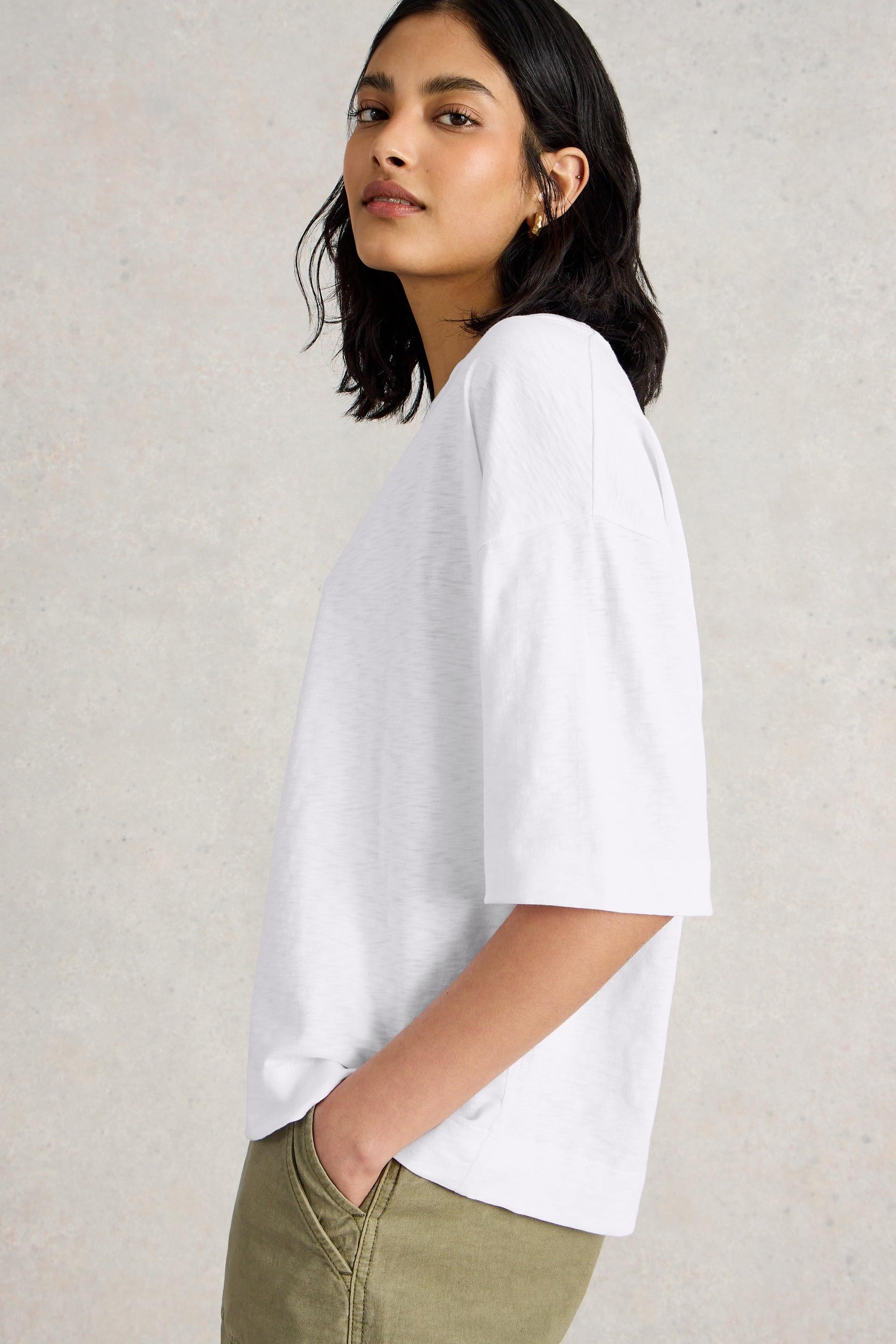 Model wearing a boxy white stuff tee paired with green trousers